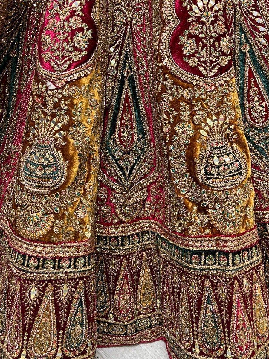 Luxury Indian lehenga with intricate gold embroidery, mirror work, and velvet fabric in maroon and gold tones