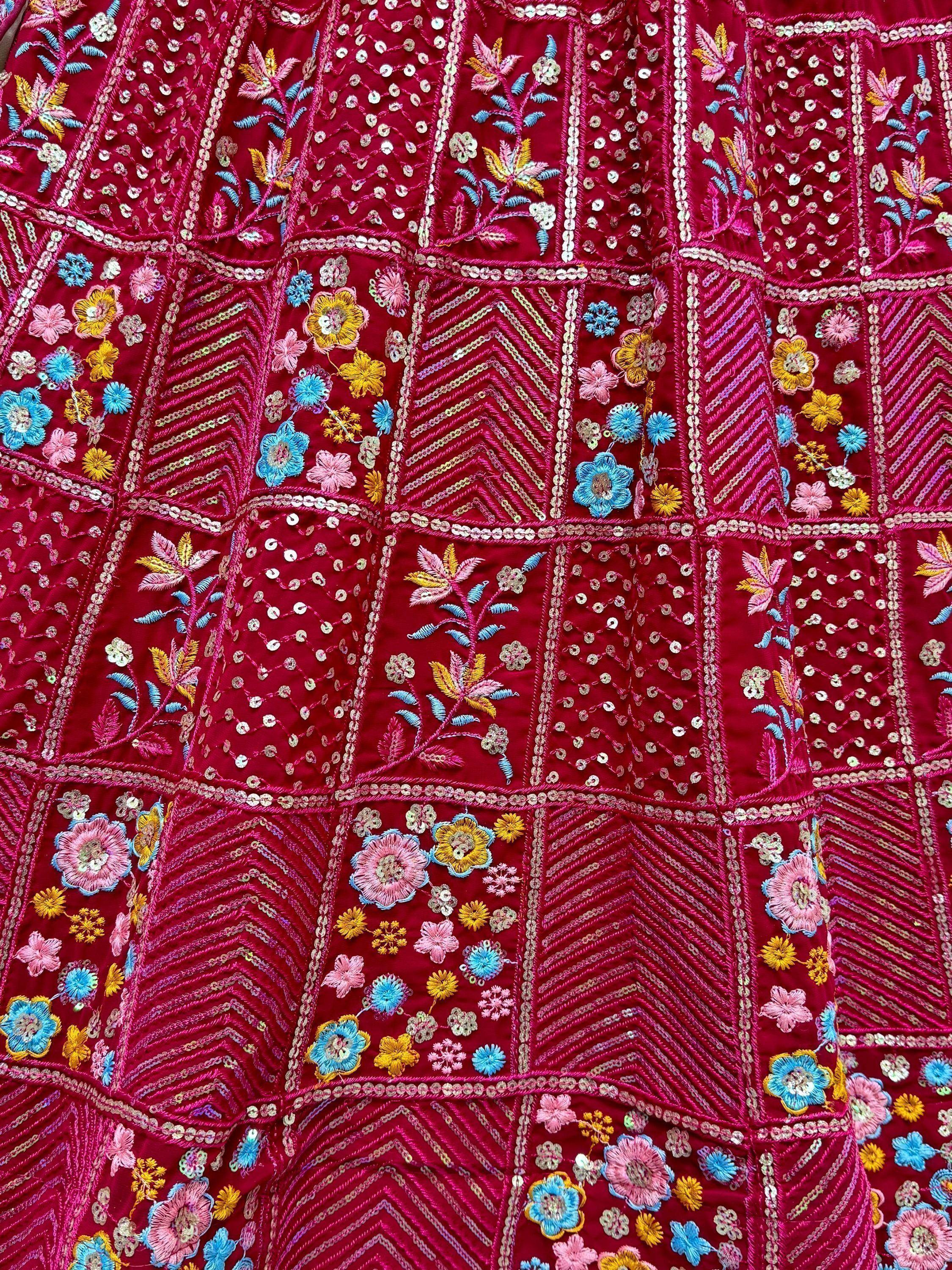 Richly embroidered red ethnic wear with floral motifs, sequins, and geometric patterns for festive occasions.
