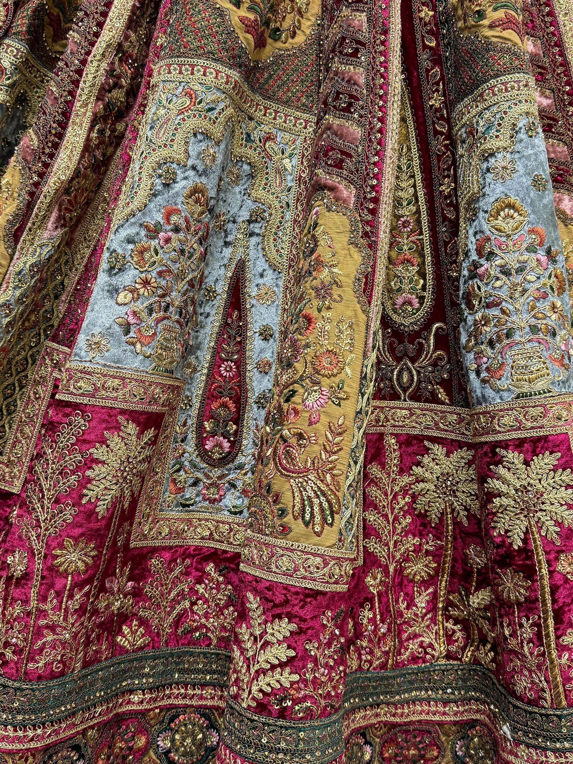 Luxury Indian ethnic wear with intricate gold embroidery, floral motifs, and rich velvet fabric in maroon and grey tones.
