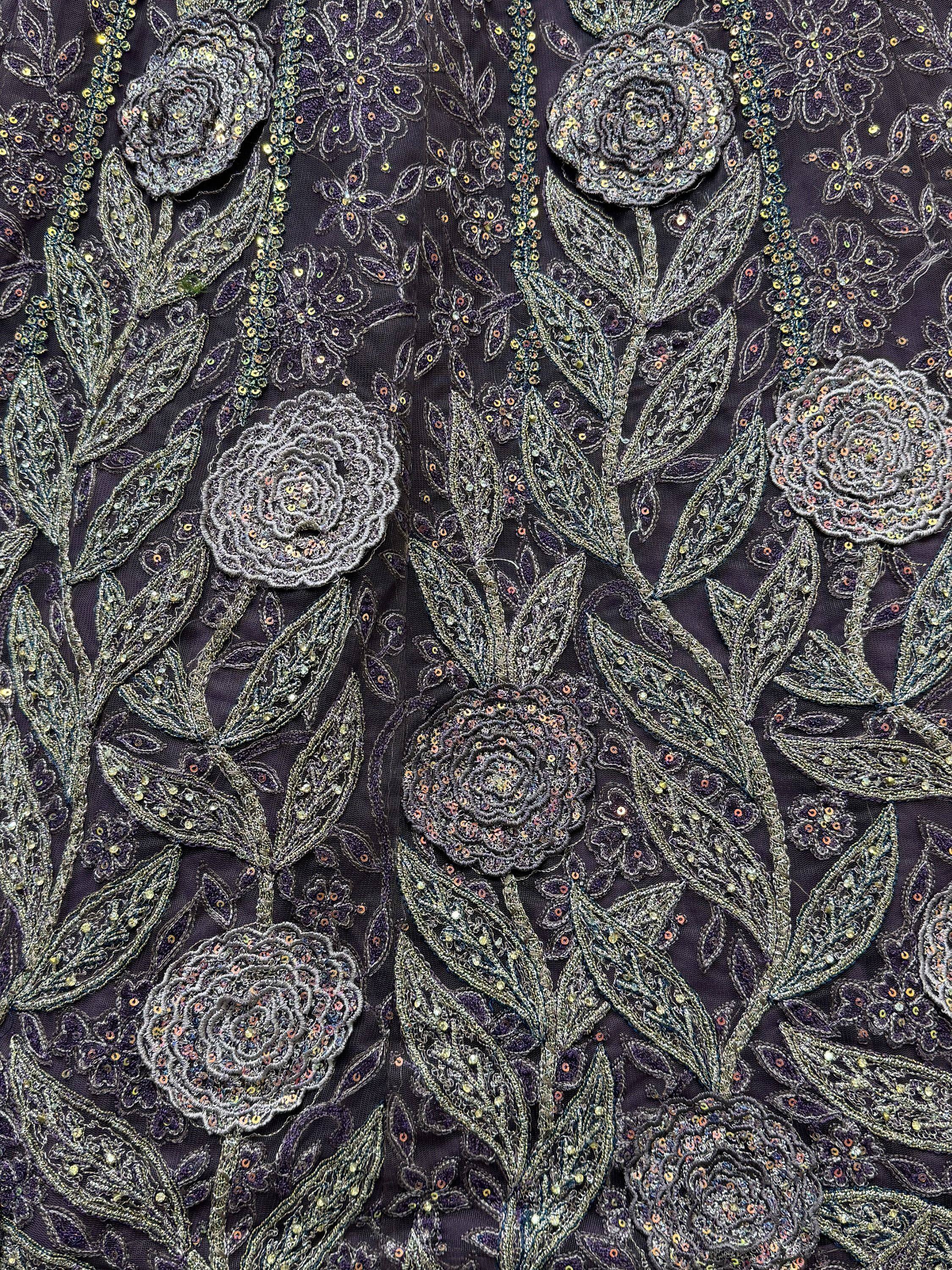 Dark purple ethnic wear fabric with intricate floral embroidery and shimmering sequins for designer lehenga or saree.