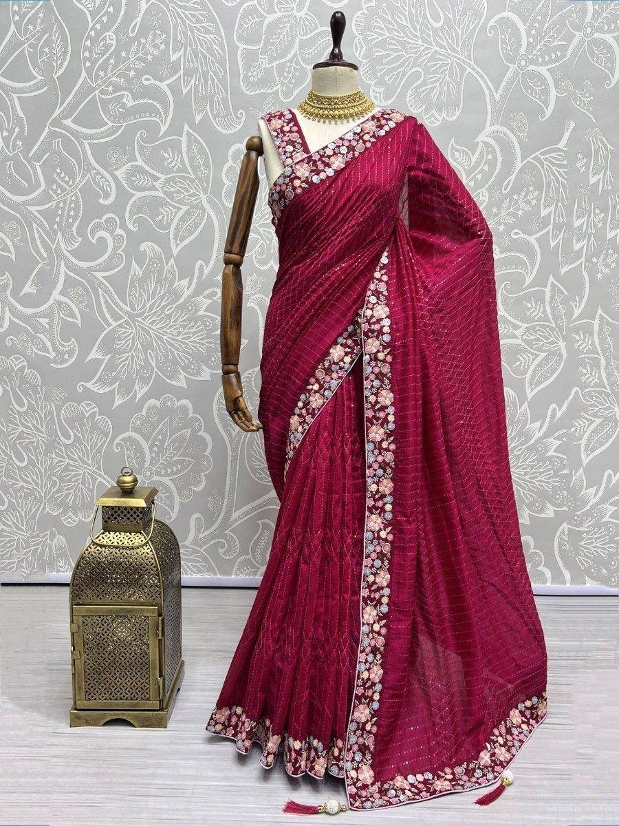 Elegant maroon saree with floral embroidery and gold necklace, displayed on mannequin with decorative lantern