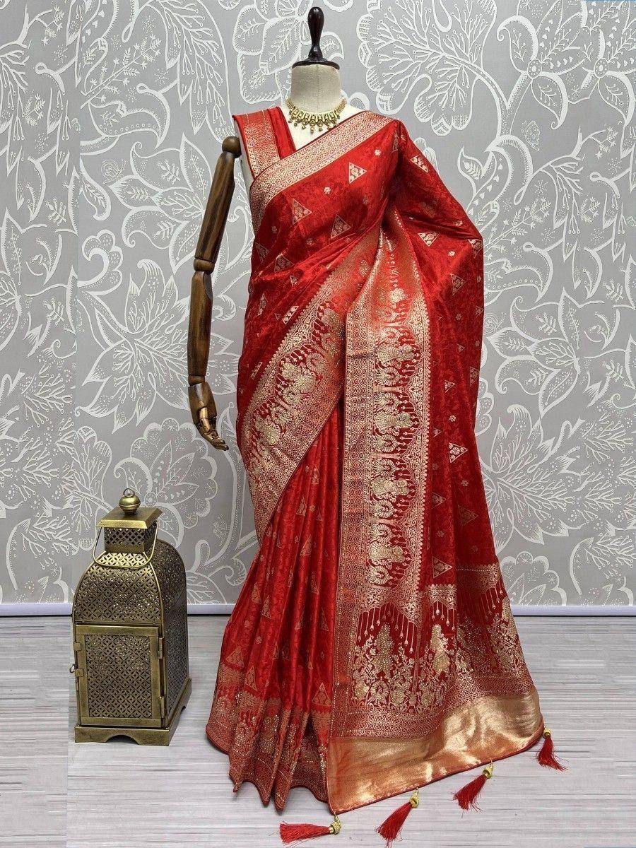 Red and gold designer saree with intricate embroidery and tassels, displayed on mannequin with decorative lantern