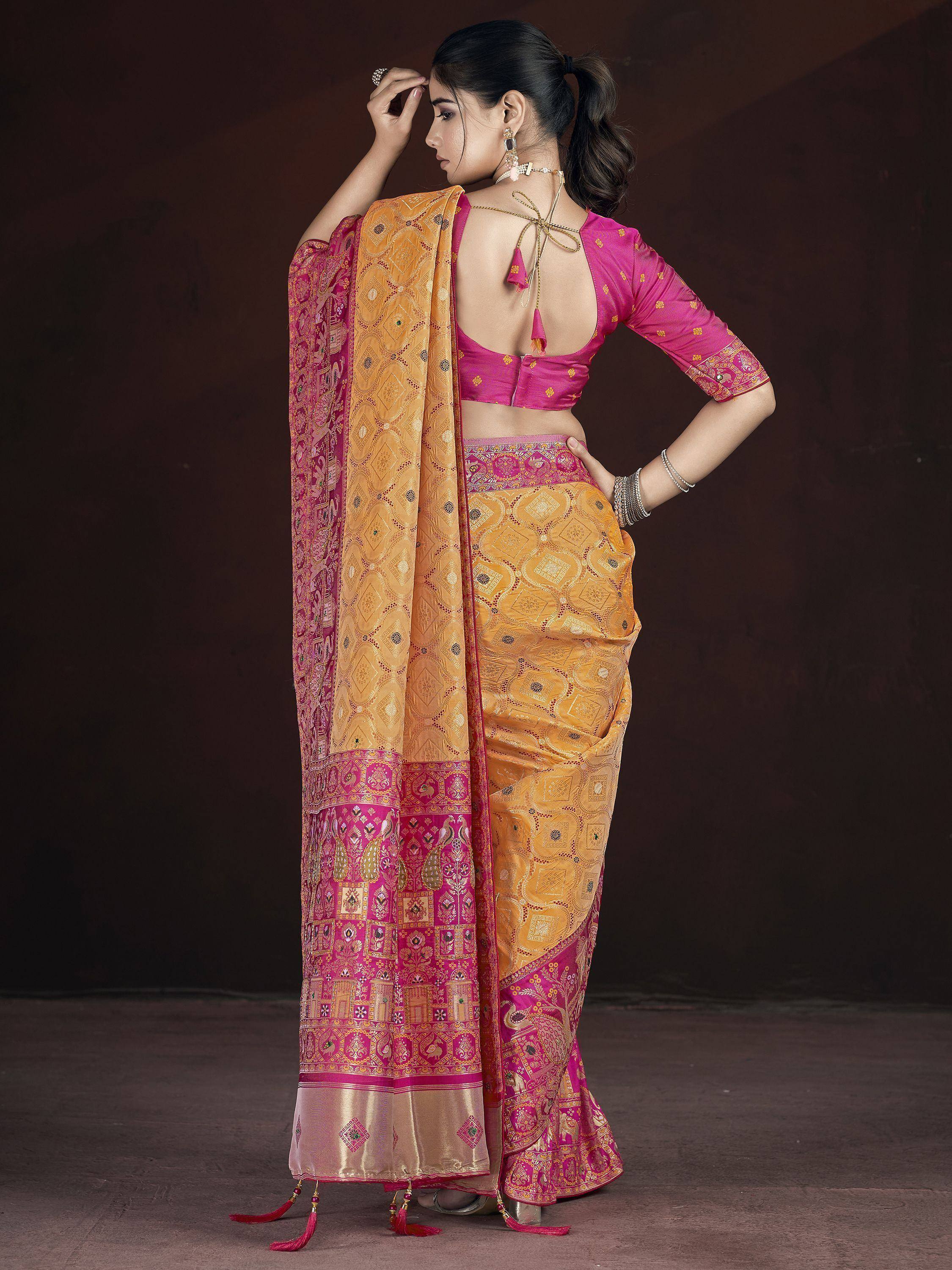 Woman in vibrant yellow and pink designer saree with intricate patterns and backless blouse, ethnic wear