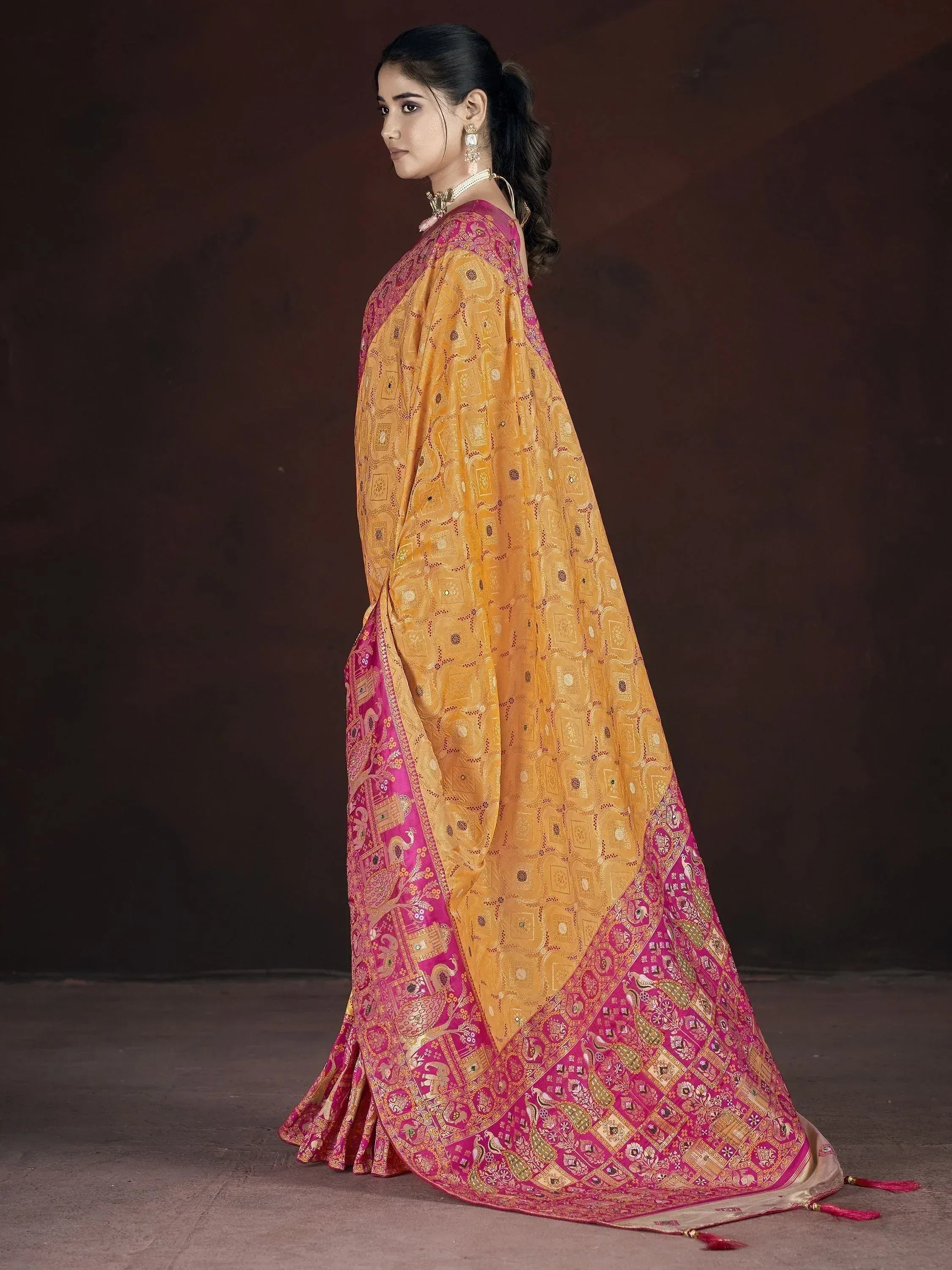 Woman in elegant yellow and pink ethnic saree with intricate paisley and geometric patterns, perfect for Indian occasions.