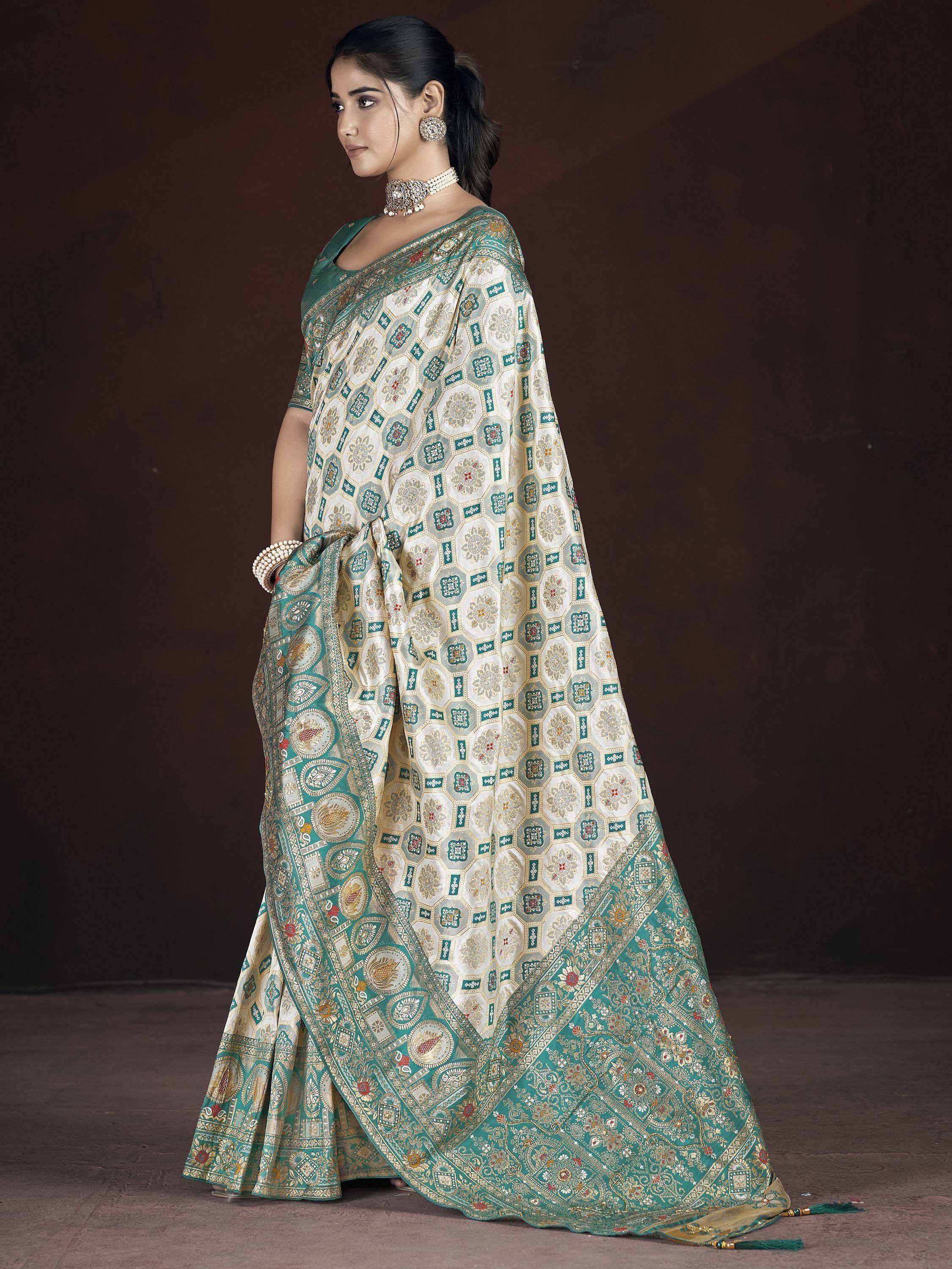 Elegant teal and cream designer saree with intricate geometric and floral embroidery, perfect for Indian ethnic wear.