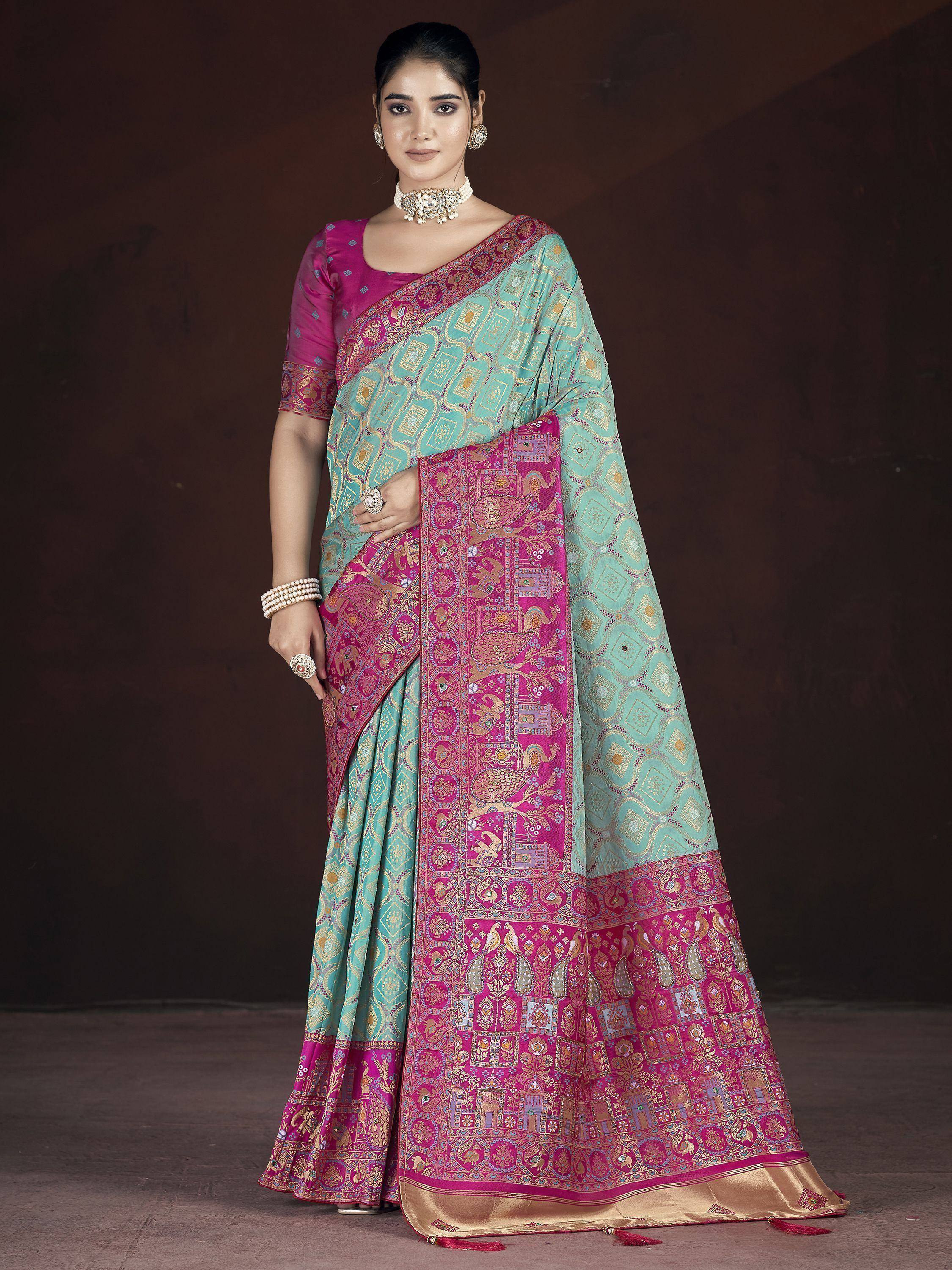 Turquoise and magenta designer saree with intricate gold embroidery and traditional Indian motifs, paired with matching blouse.