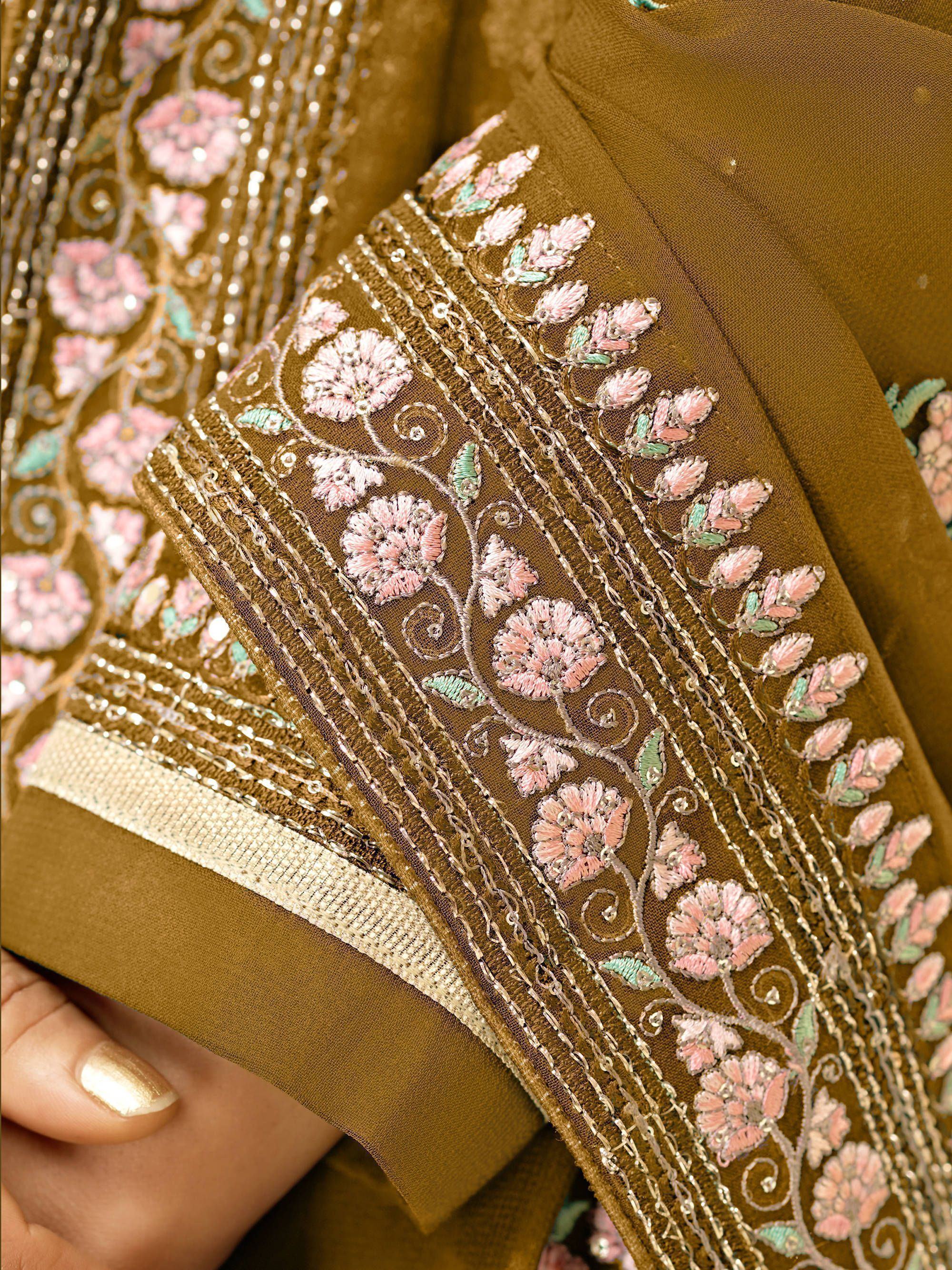 Close-up of brown ethnic saree with pink floral embroidery and gold sequin detailing
