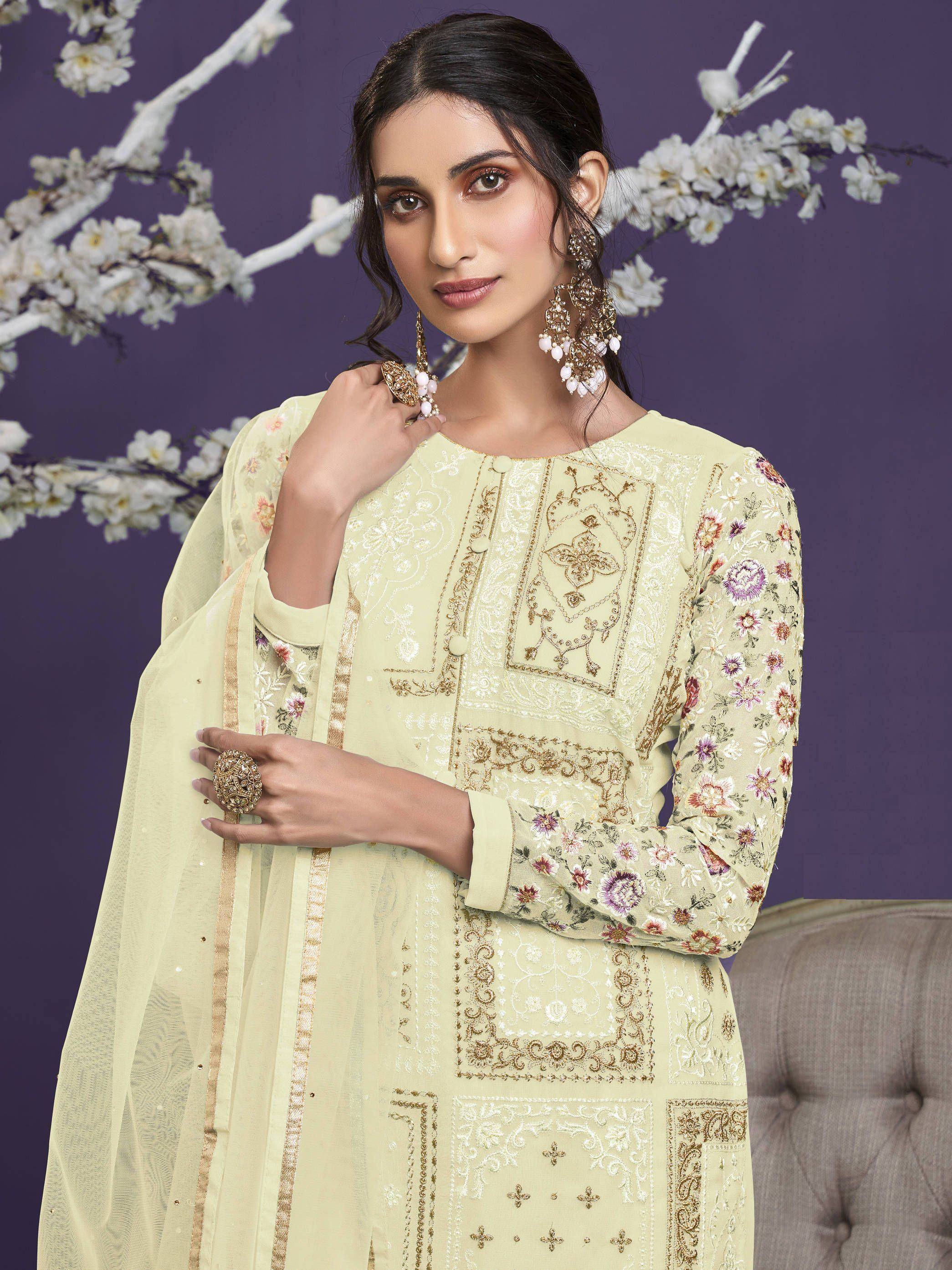 Woman in light yellow embroidered salwar kameez with floral designs and statement jewelry