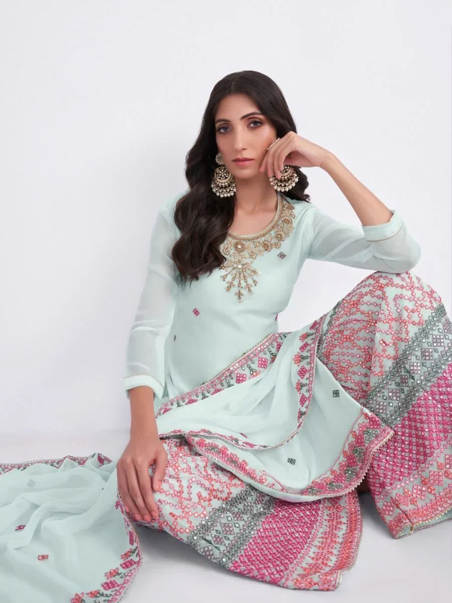 Woman in pastel green embroidered lehenga choli with pink patterns and statement earrings