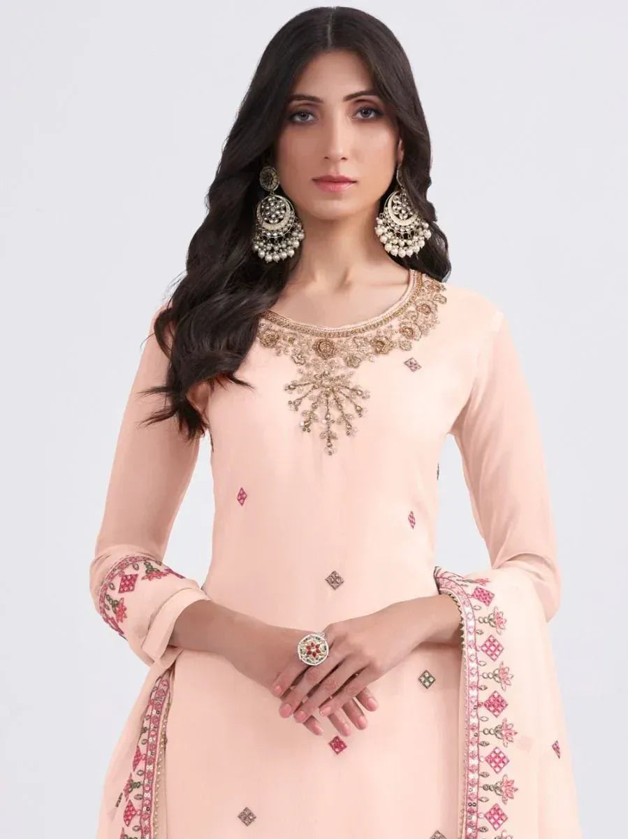 Elegant peach salwar kameez with intricate embroidery and embellished neckline