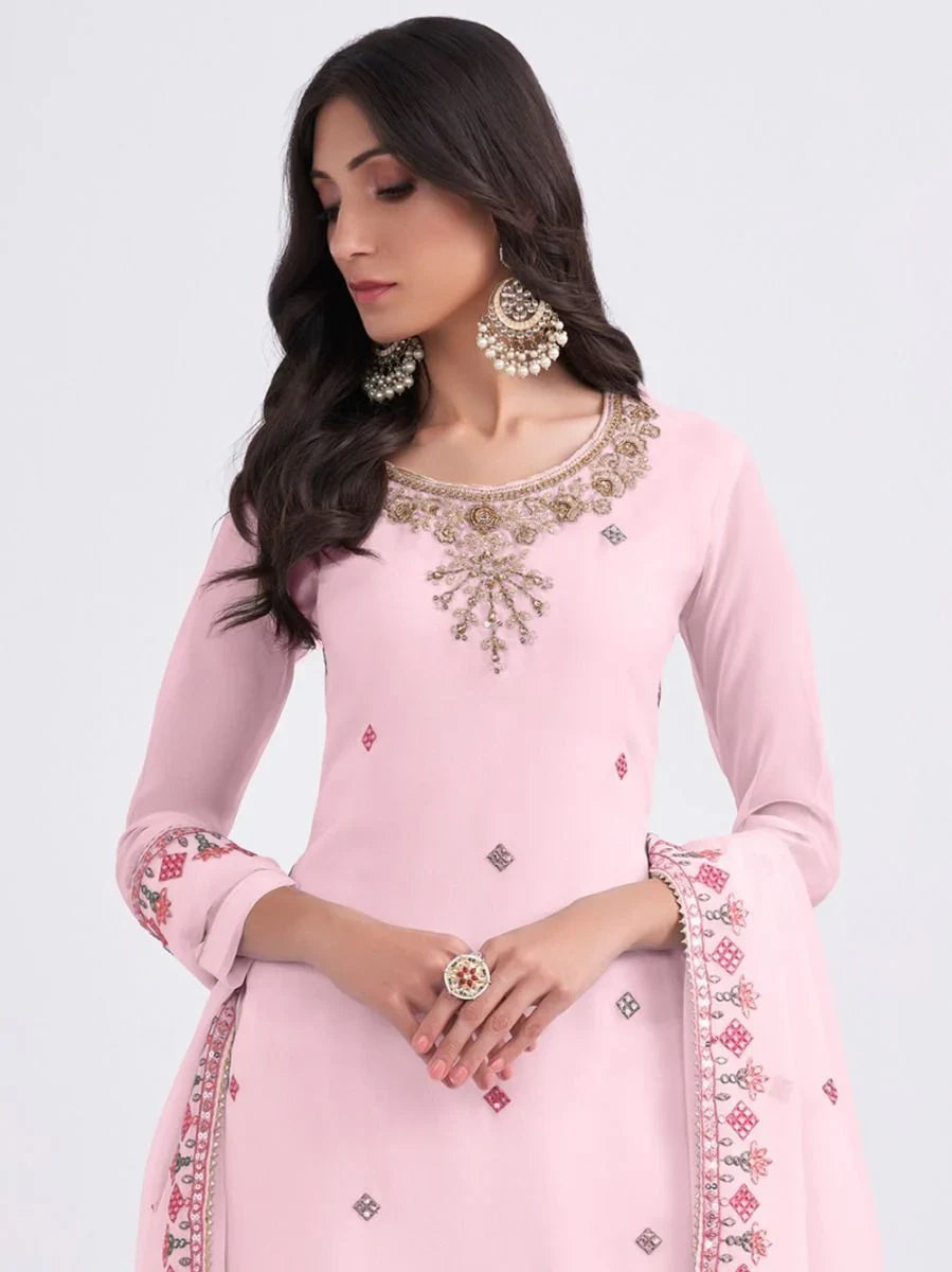 Woman in light pink embroidered salwar kameez with dupatta and statement earrings