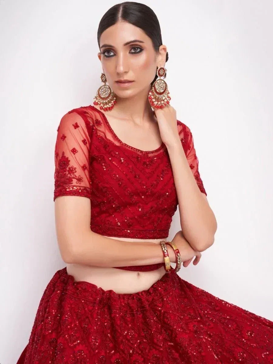 Red embroidered lehenga choli with sheer sleeves and statement earrings, perfect for Indian ethnic wear