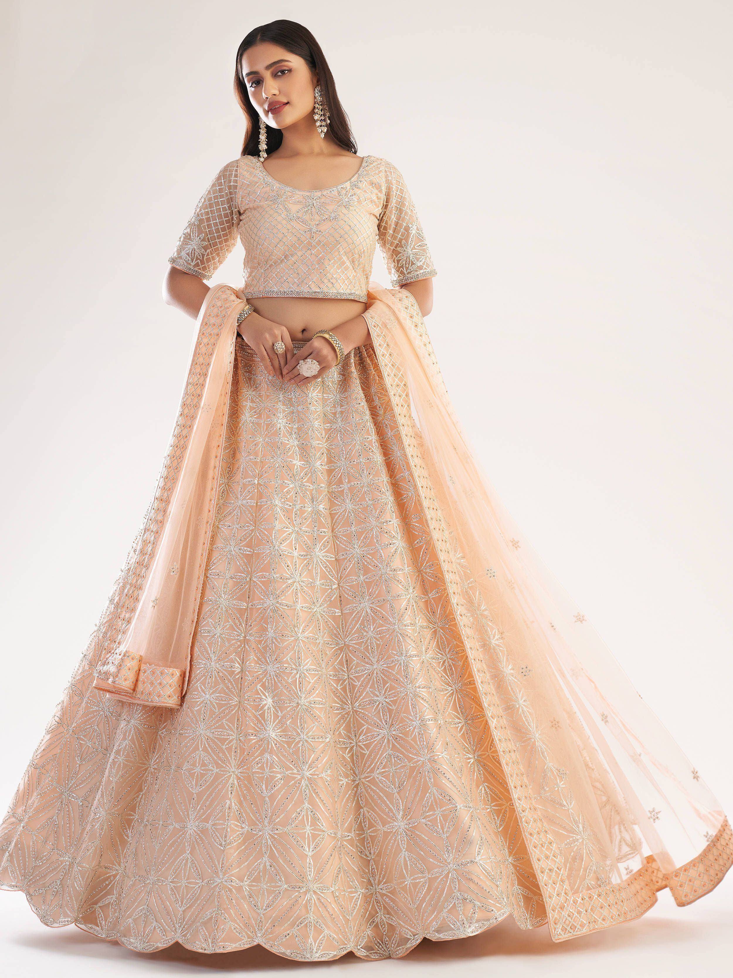 Elegant peach lehenga choli with intricate silver embroidery and sheer dupatta, perfect for Indian weddings and festive occasions.