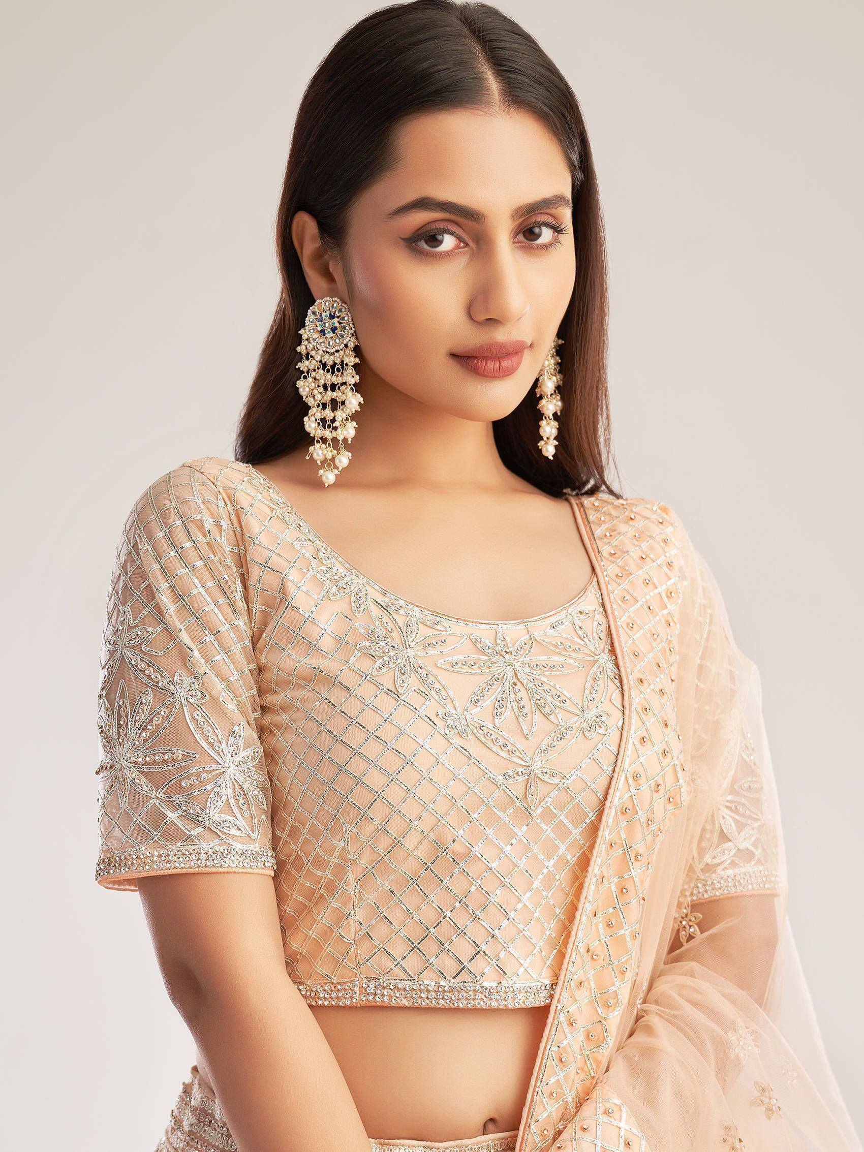 Elegant peach lehenga choli with silver embroidery and pearl earrings, perfect for Indian ethnic wear.