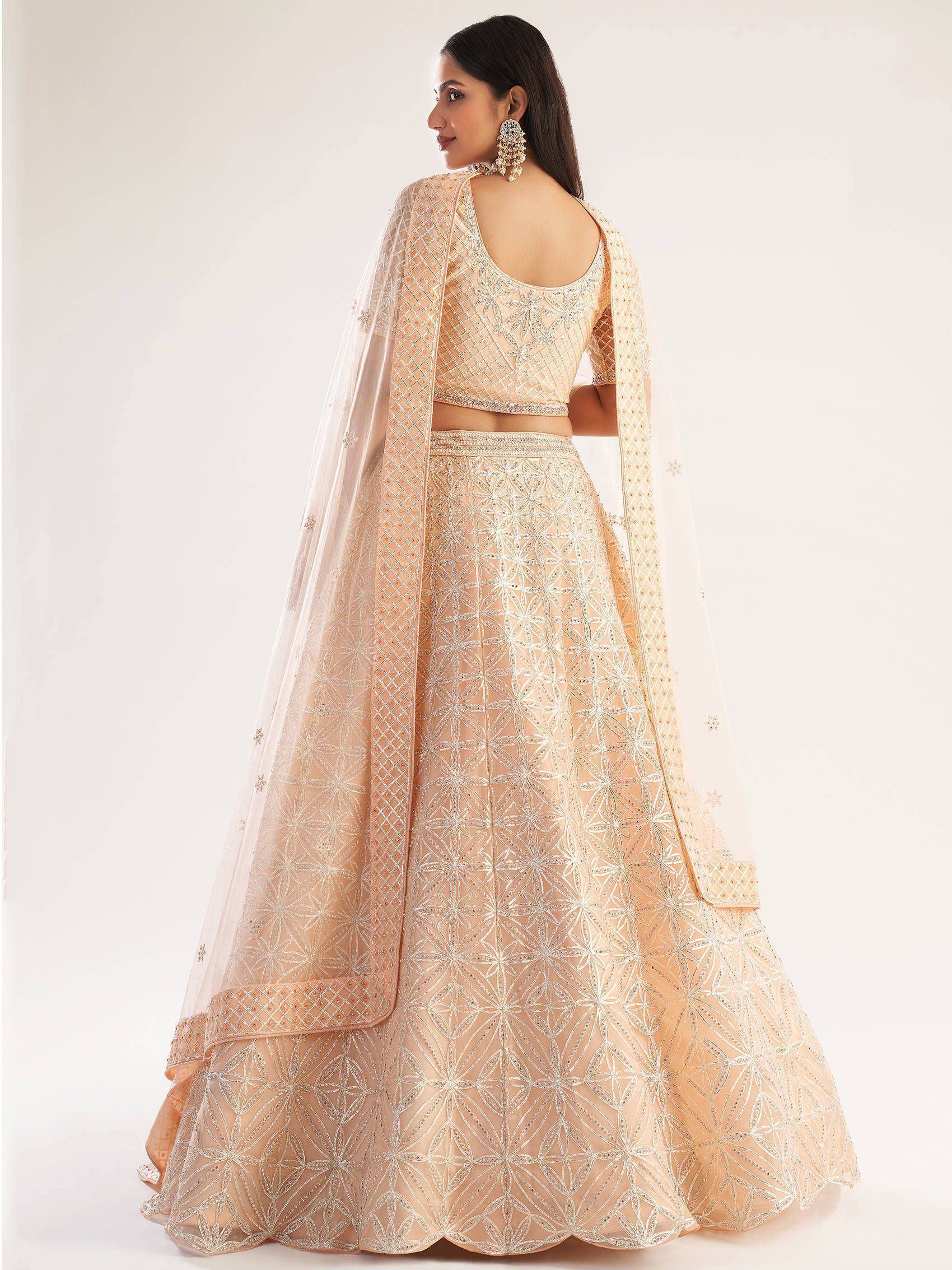 Elegant peach lehenga choli with intricate silver embroidery and sheer dupatta, perfect for Indian weddings and festive occasions.