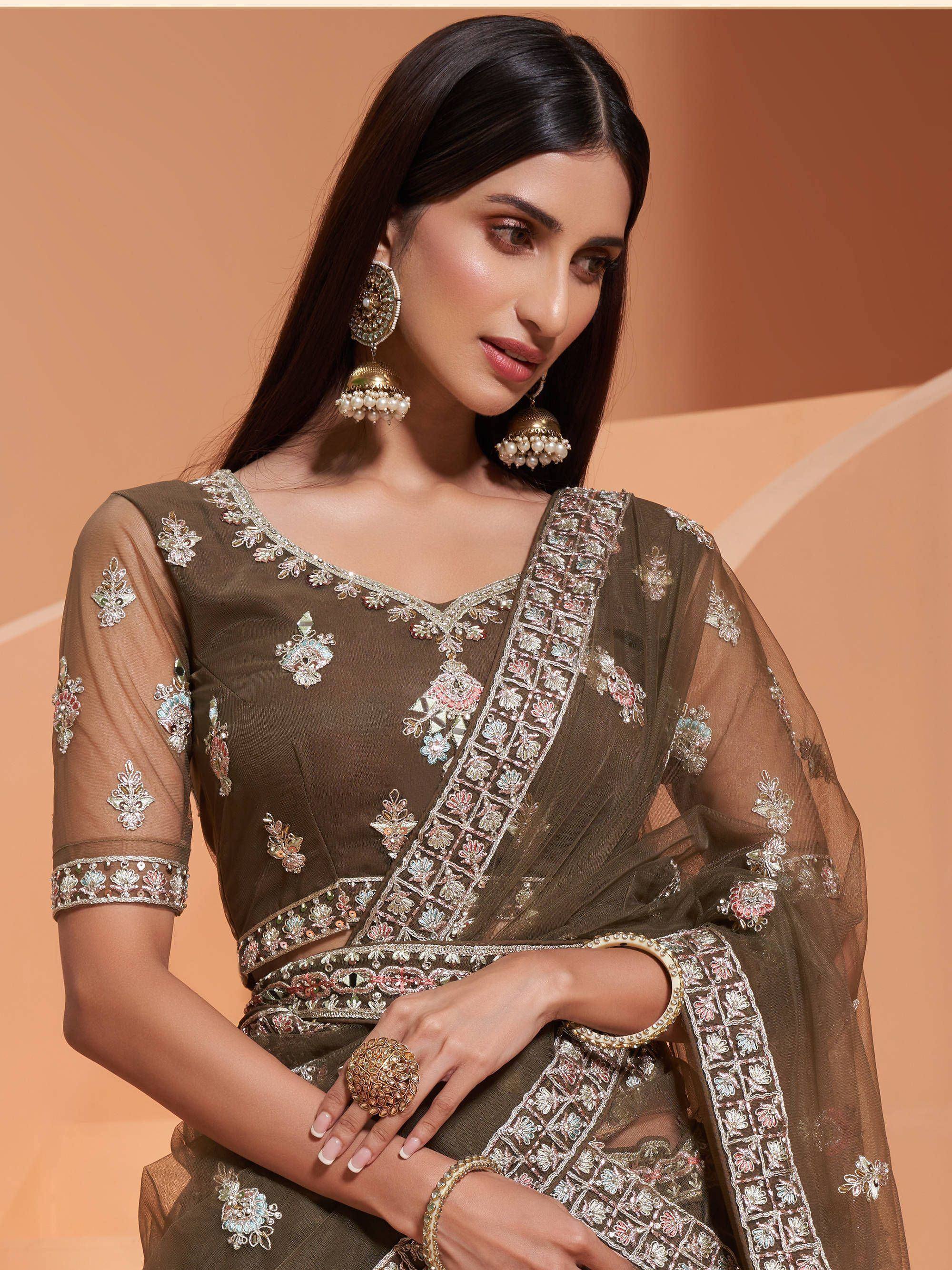 Olive green embroidered saree with floral motifs and sheer sleeves, paired with statement jhumka earrings