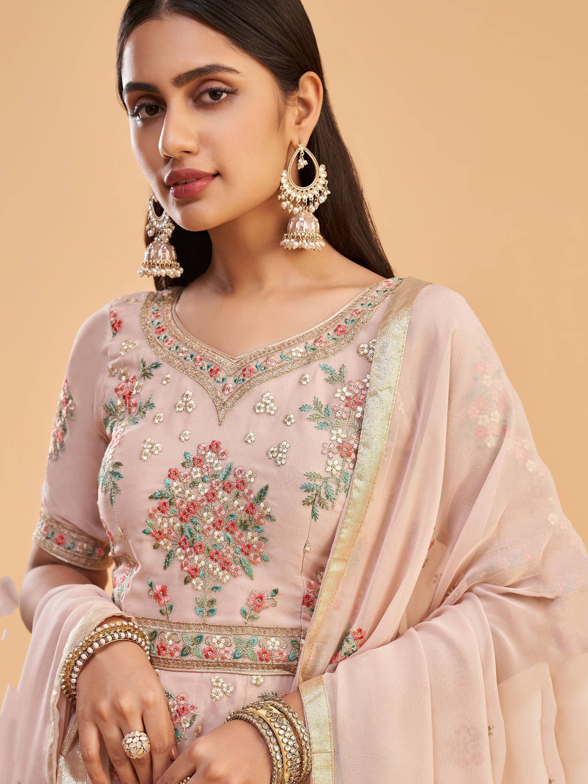 Elegant pink embroidered salwar kameez with floral designs and gold trim, paired with jhumka earrings.