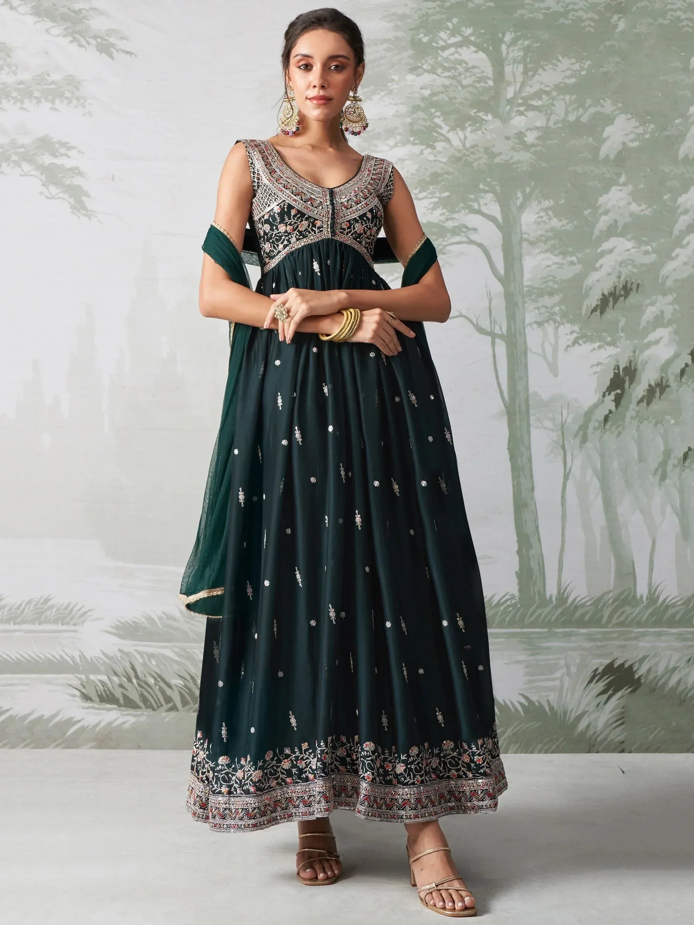 Woman wearing an embroidered dark green Anarkali suit with dupatta and gold jewelry