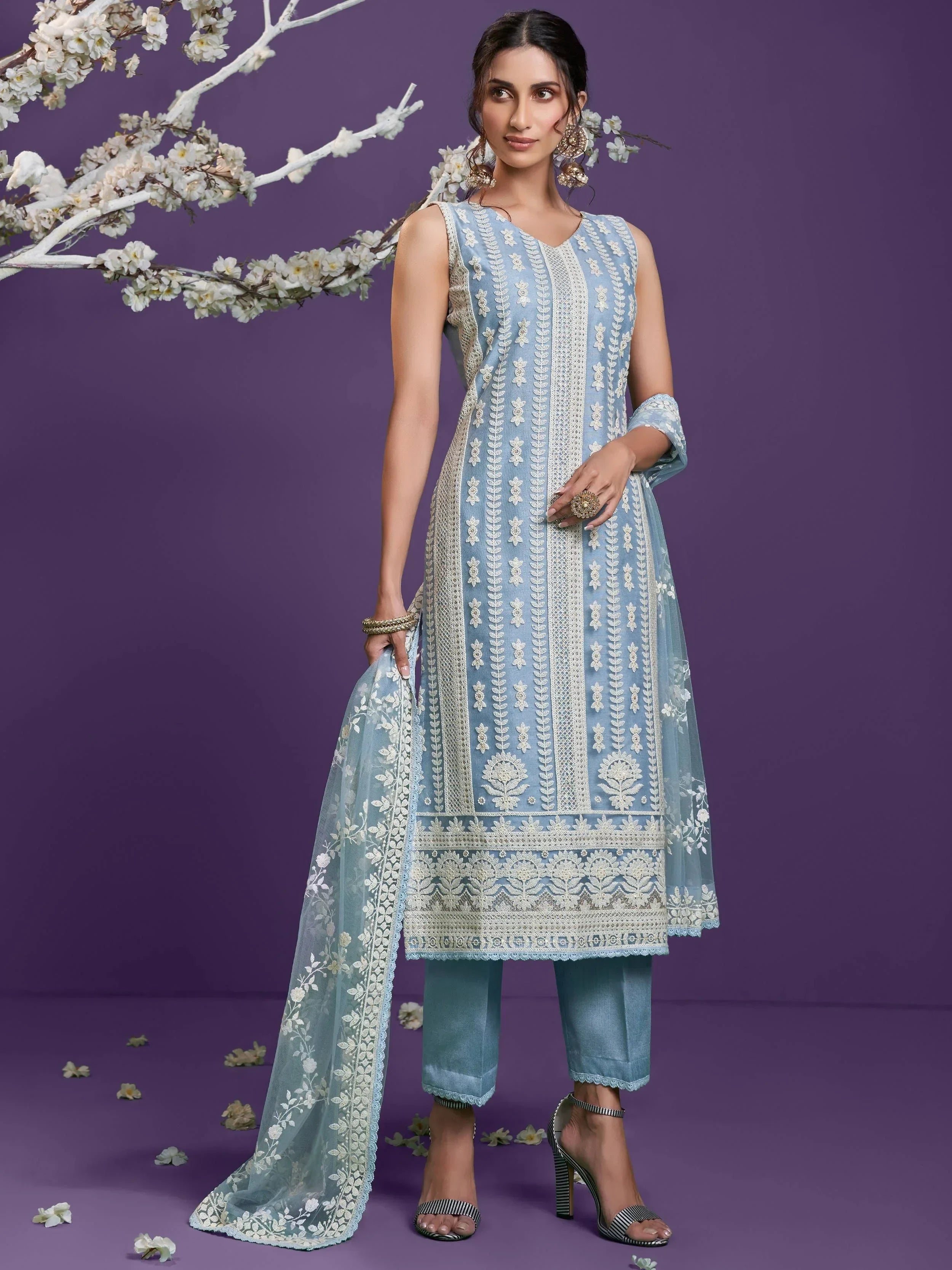 Woman wearing pastel blue embroidered Lucknowi salwar kameez with dupatta, floral backdrop