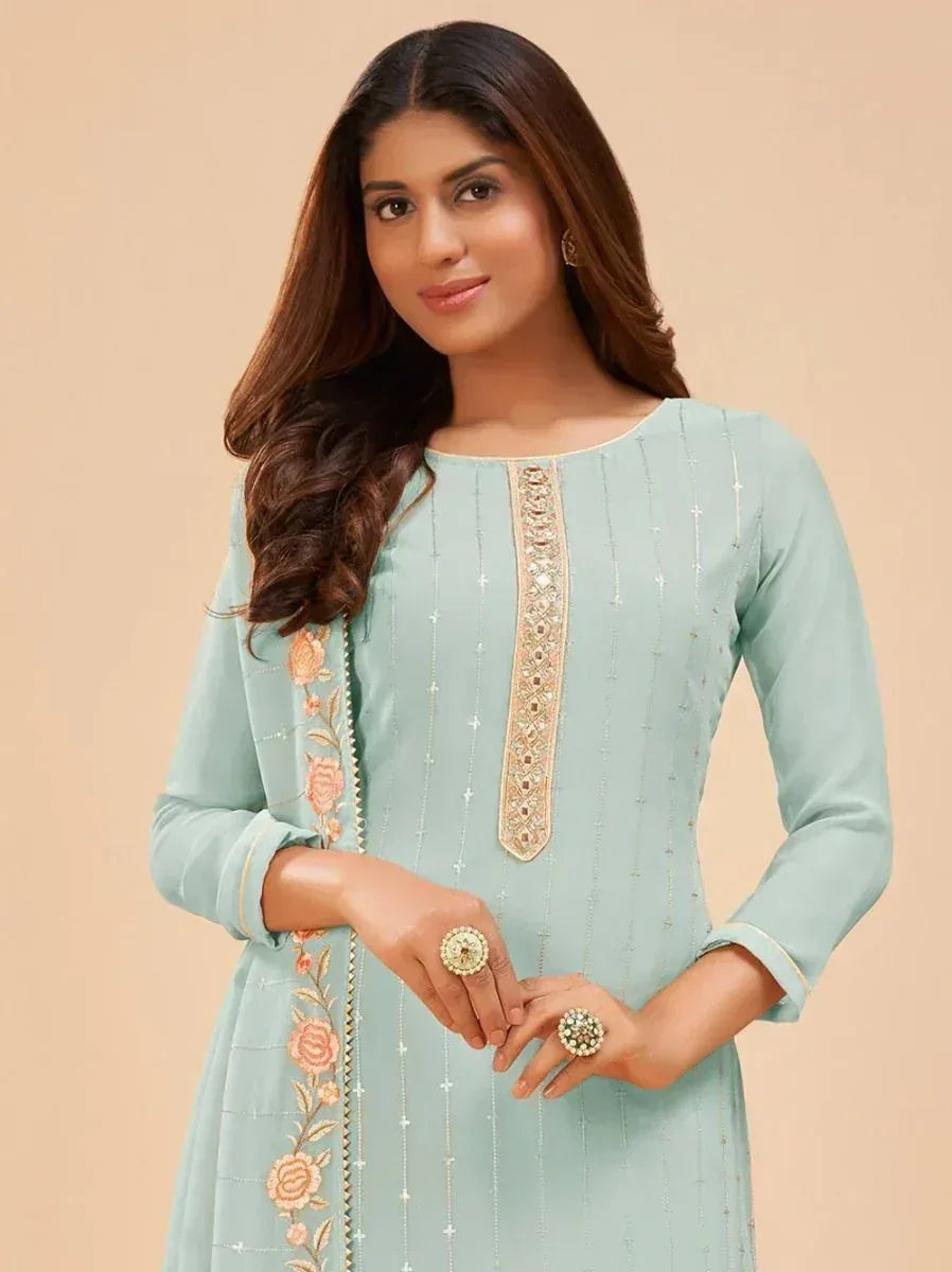 Woman in pastel blue embroidered salwar kameez with floral dupatta and statement rings