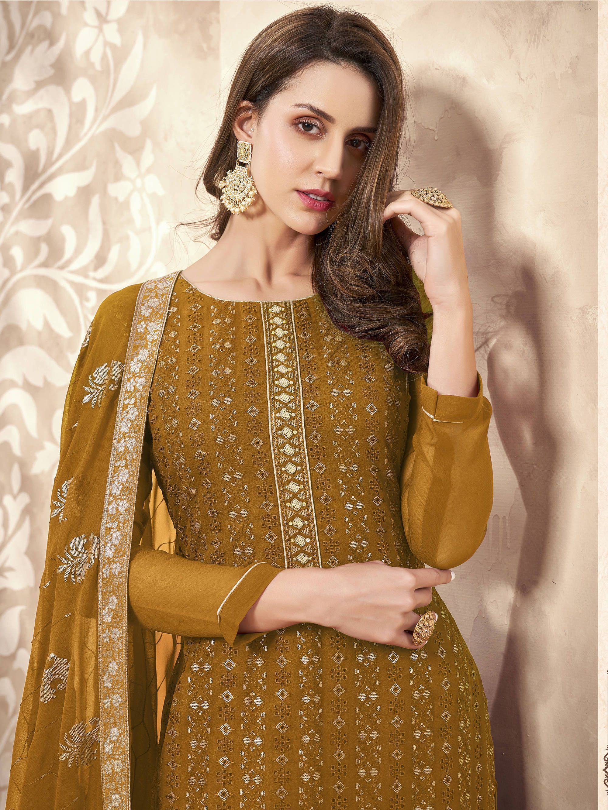 Woman in mustard embroidered salwar kameez with dupatta and statement earrings