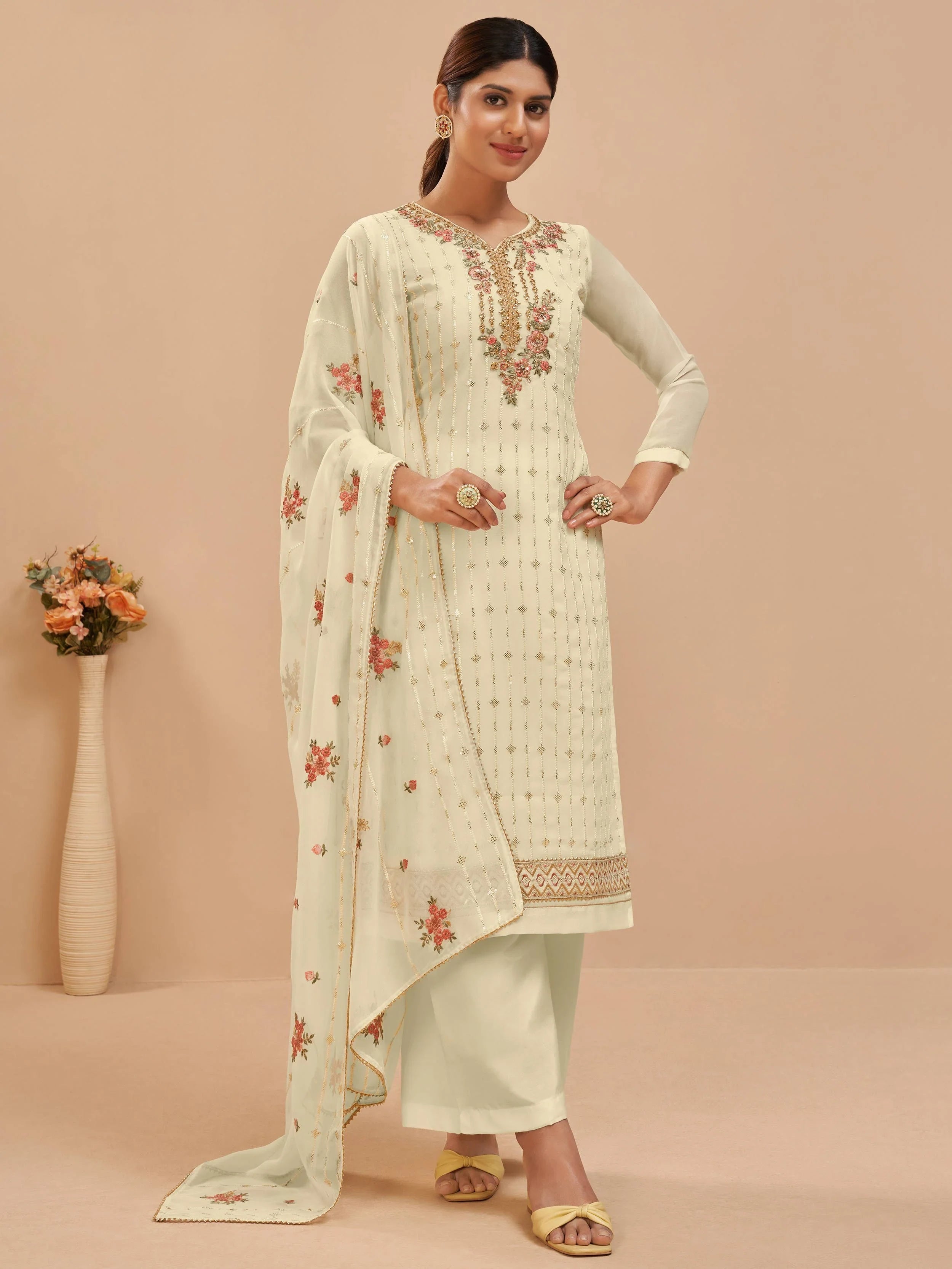 Woman in cream embroidered salwar kameez with floral dupatta and golden accessories