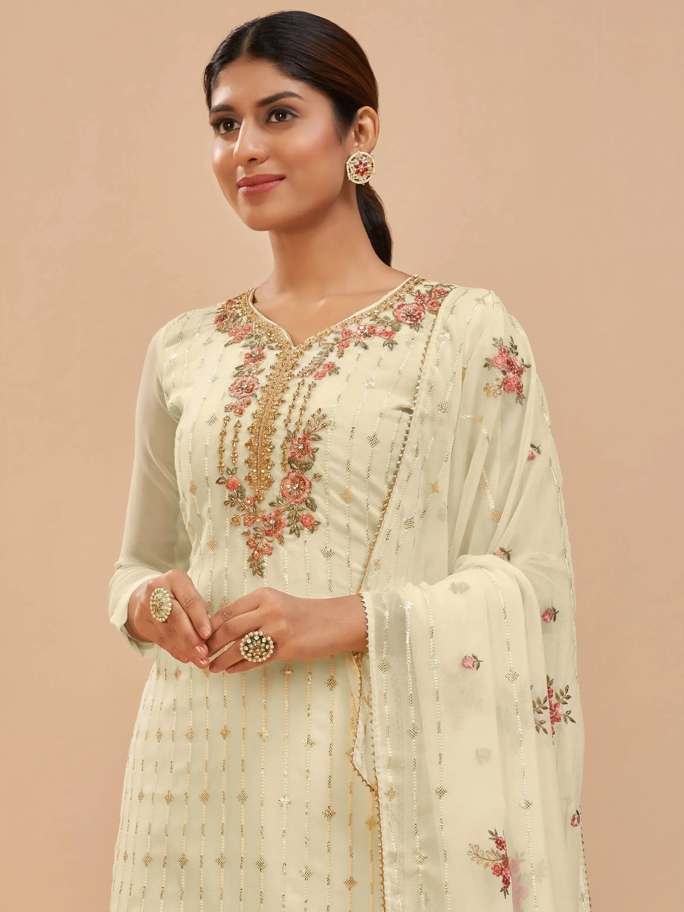 Woman in cream embroidered salwar kameez with floral dupatta and statement jewelry