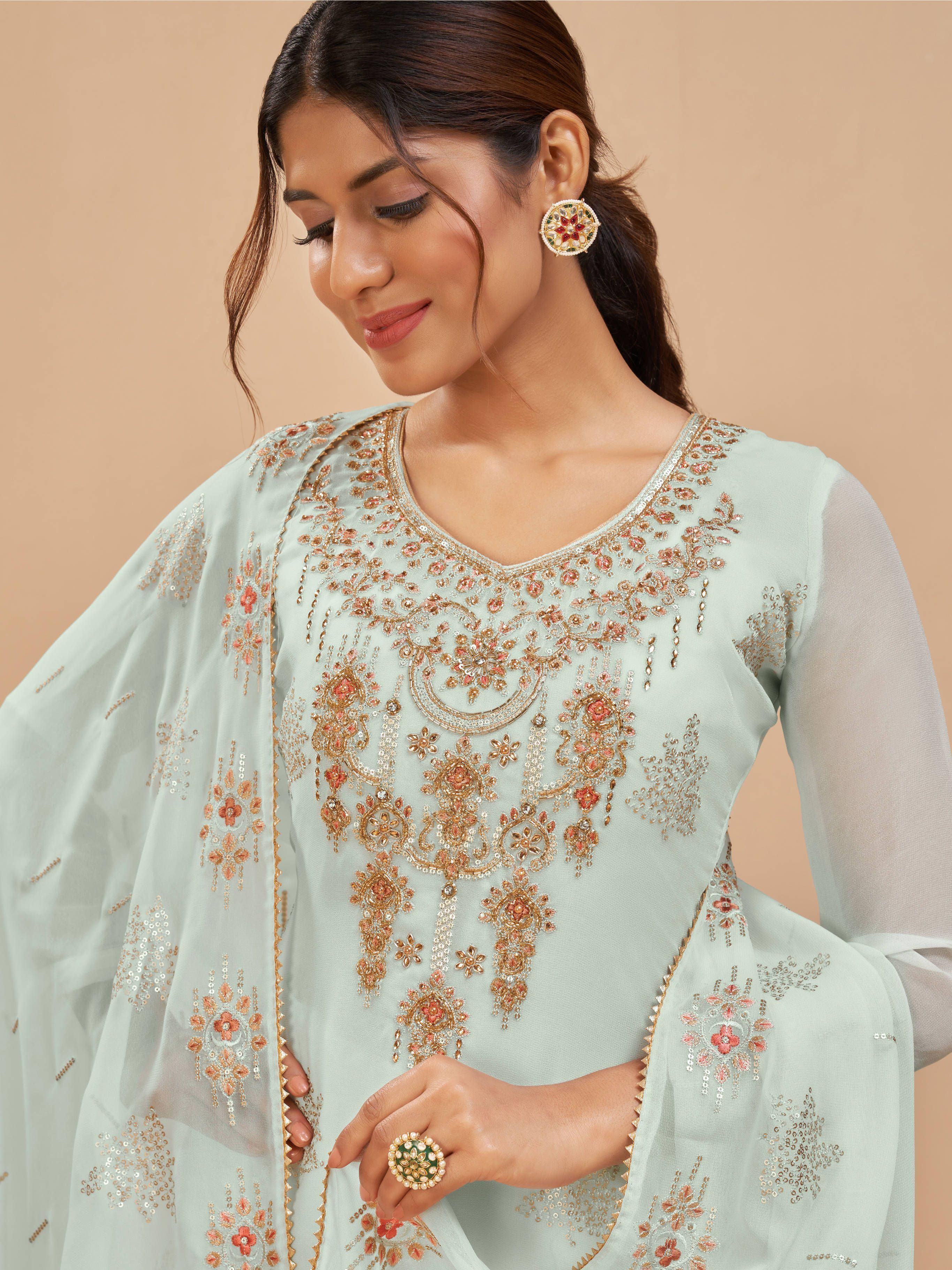 Woman in pastel green embroidered salwar kameez with matching dupatta, ethnic jewelry