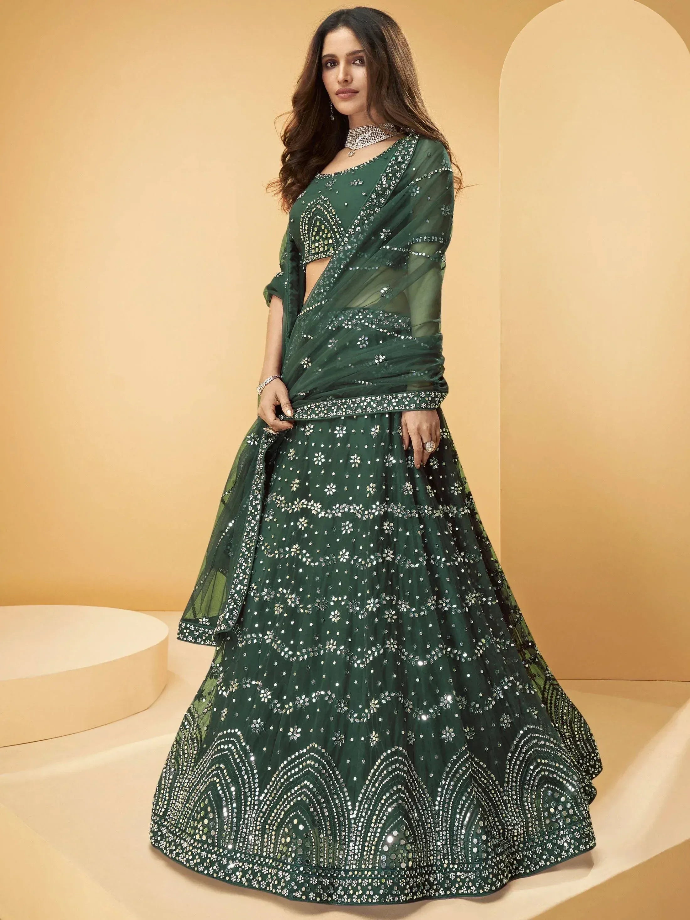 Emerald green designer lehenga choli with mirror work and sheer dupatta, perfect for Indian weddings and festive occasions.
