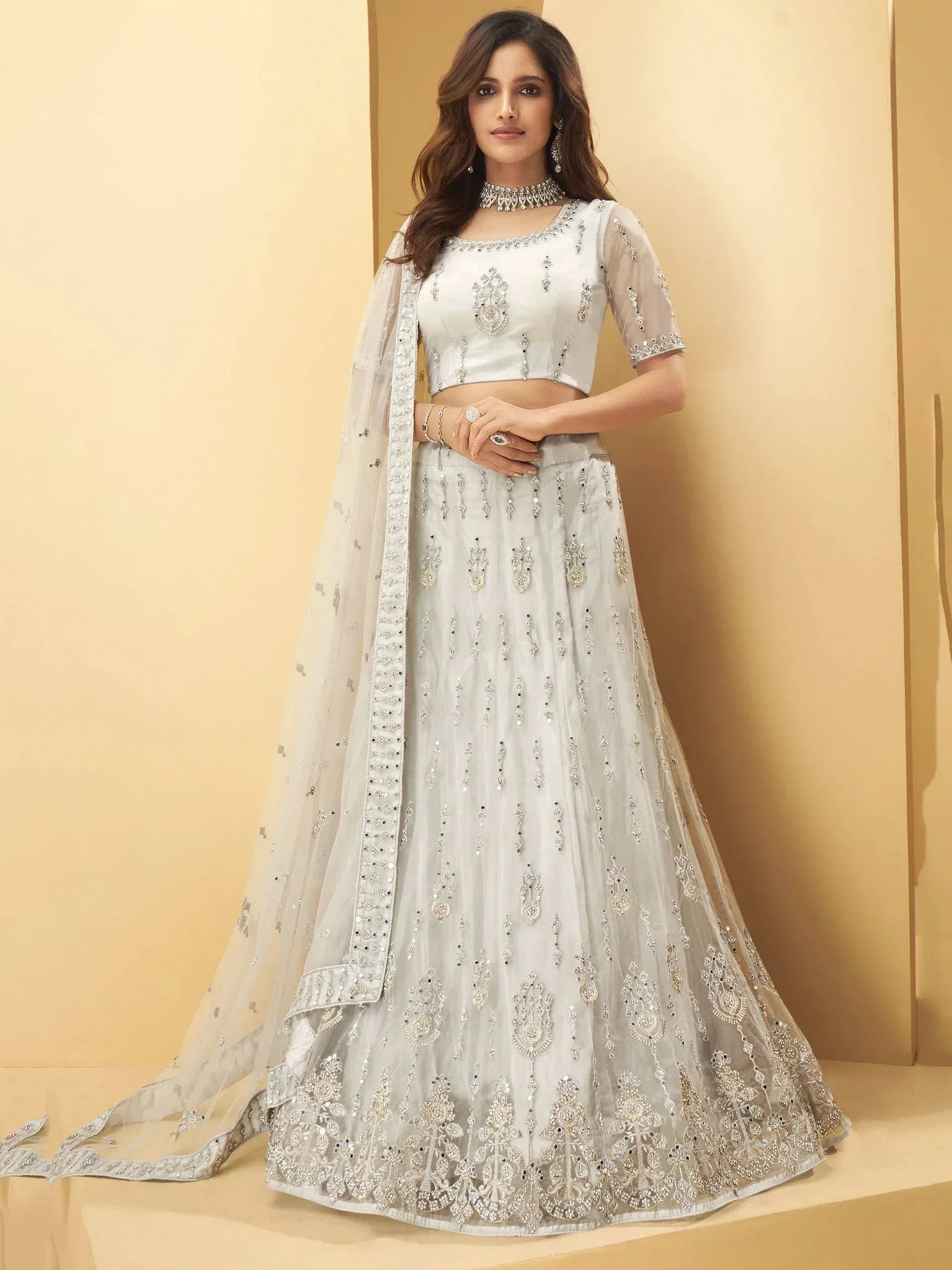 Elegant white lehenga choli with intricate silver embroidery and sheer dupatta for Indian ethnic wear