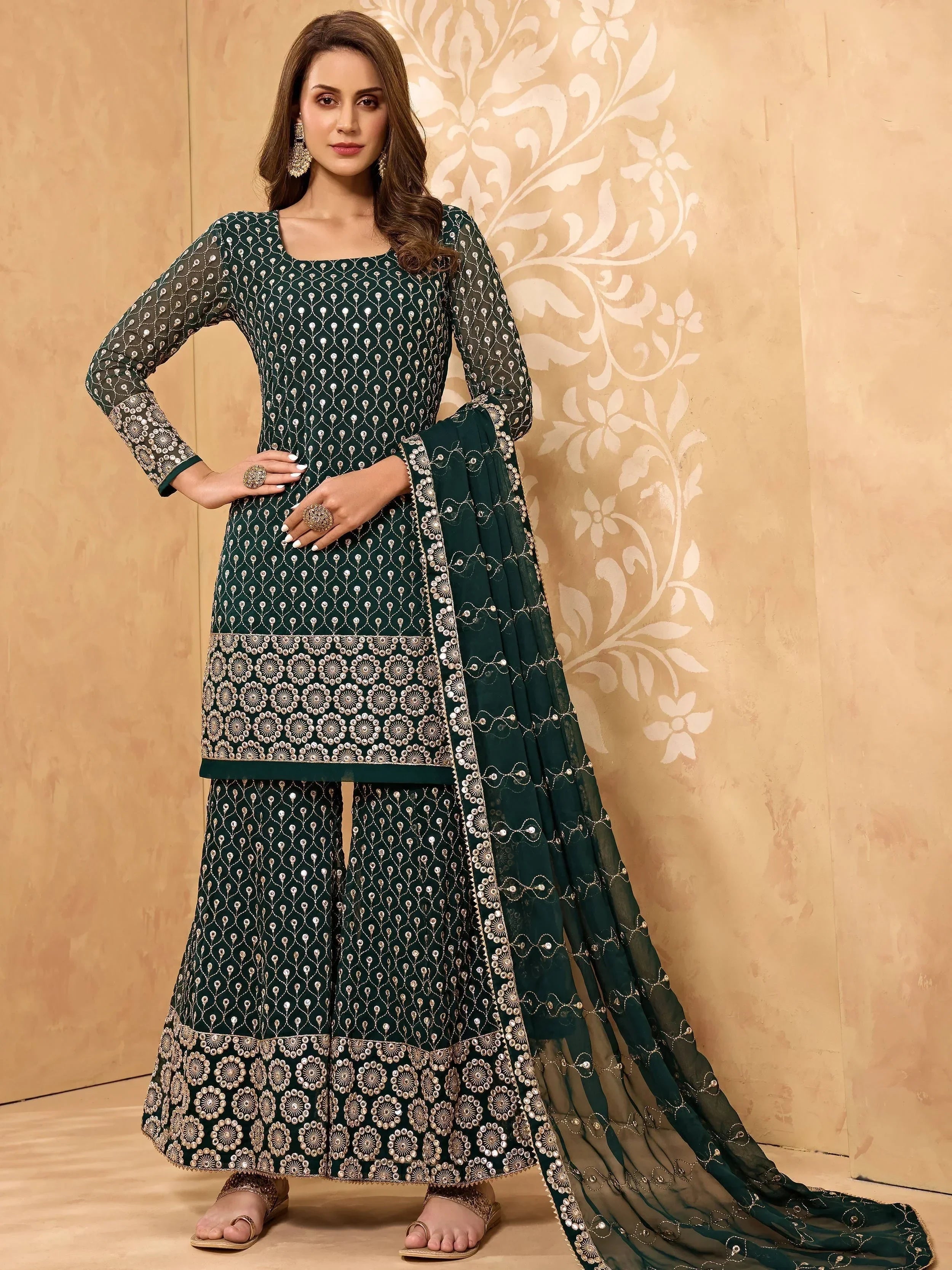 Woman in green designer salwar kameez with intricate embroidery and matching dupatta