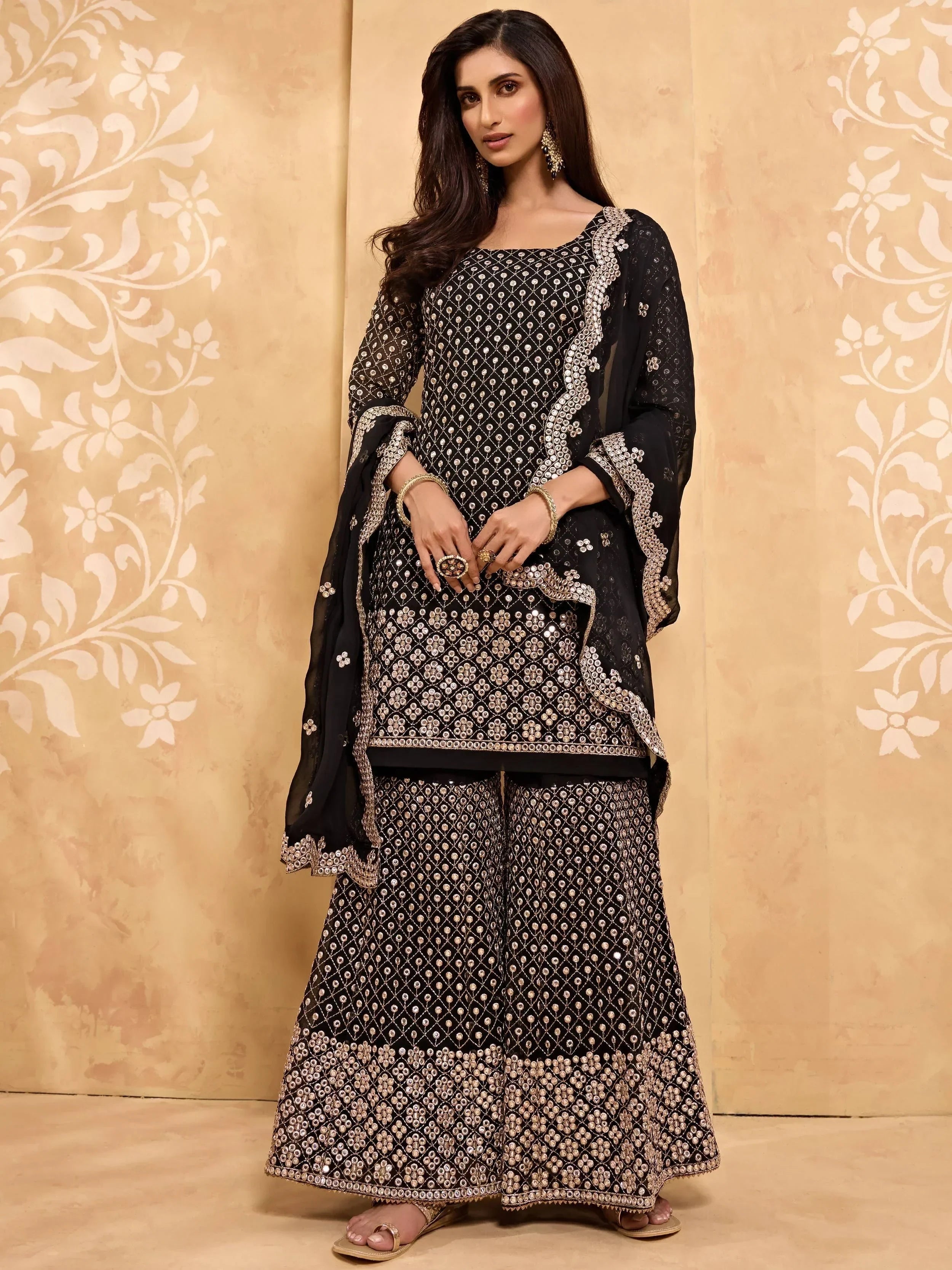 Woman wearing a black embroidered Indian palazzo salwar kameez with beige dupatta