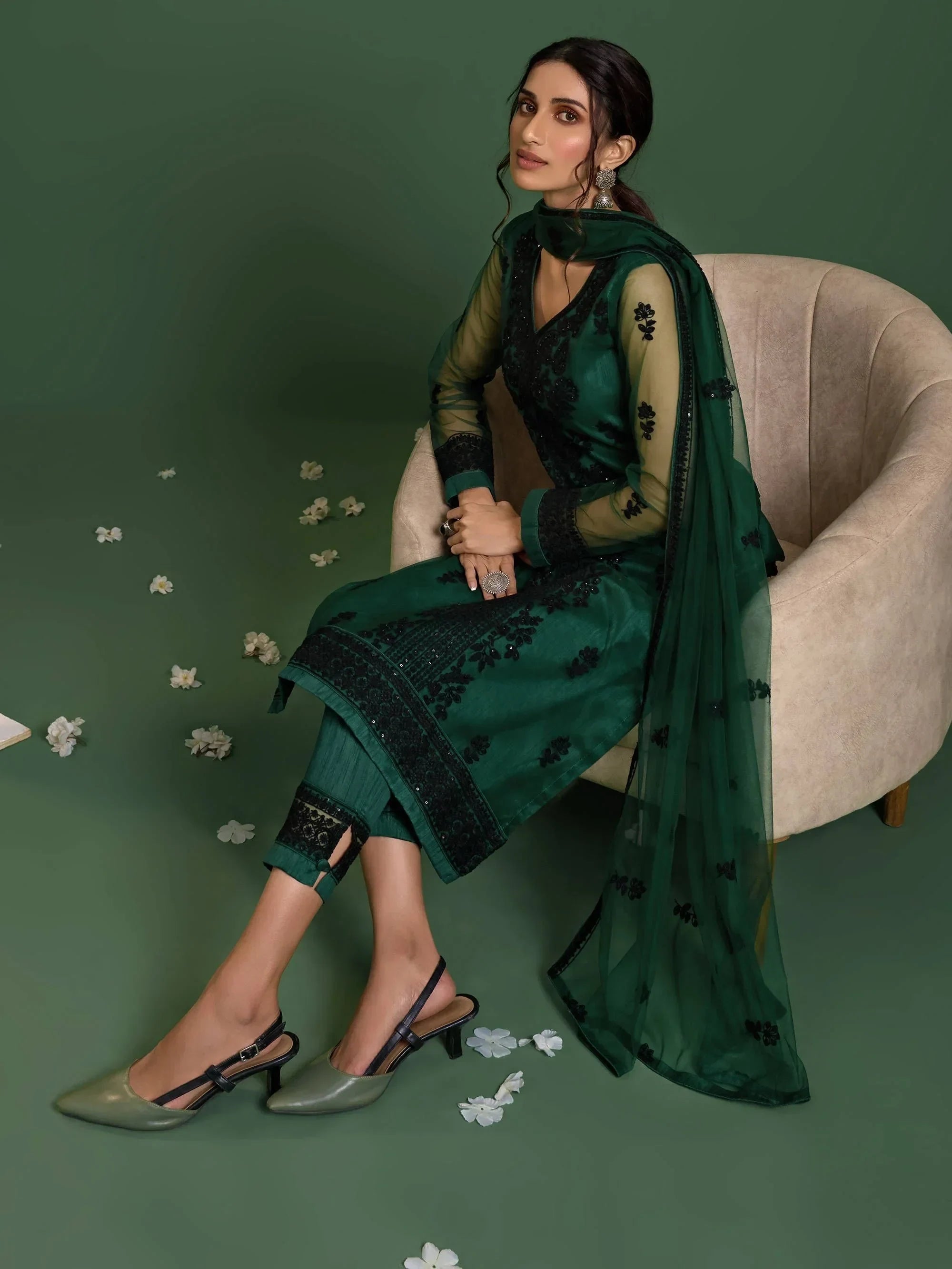Woman in elegant green embroidered salwar kameez with dupatta, sitting on chair