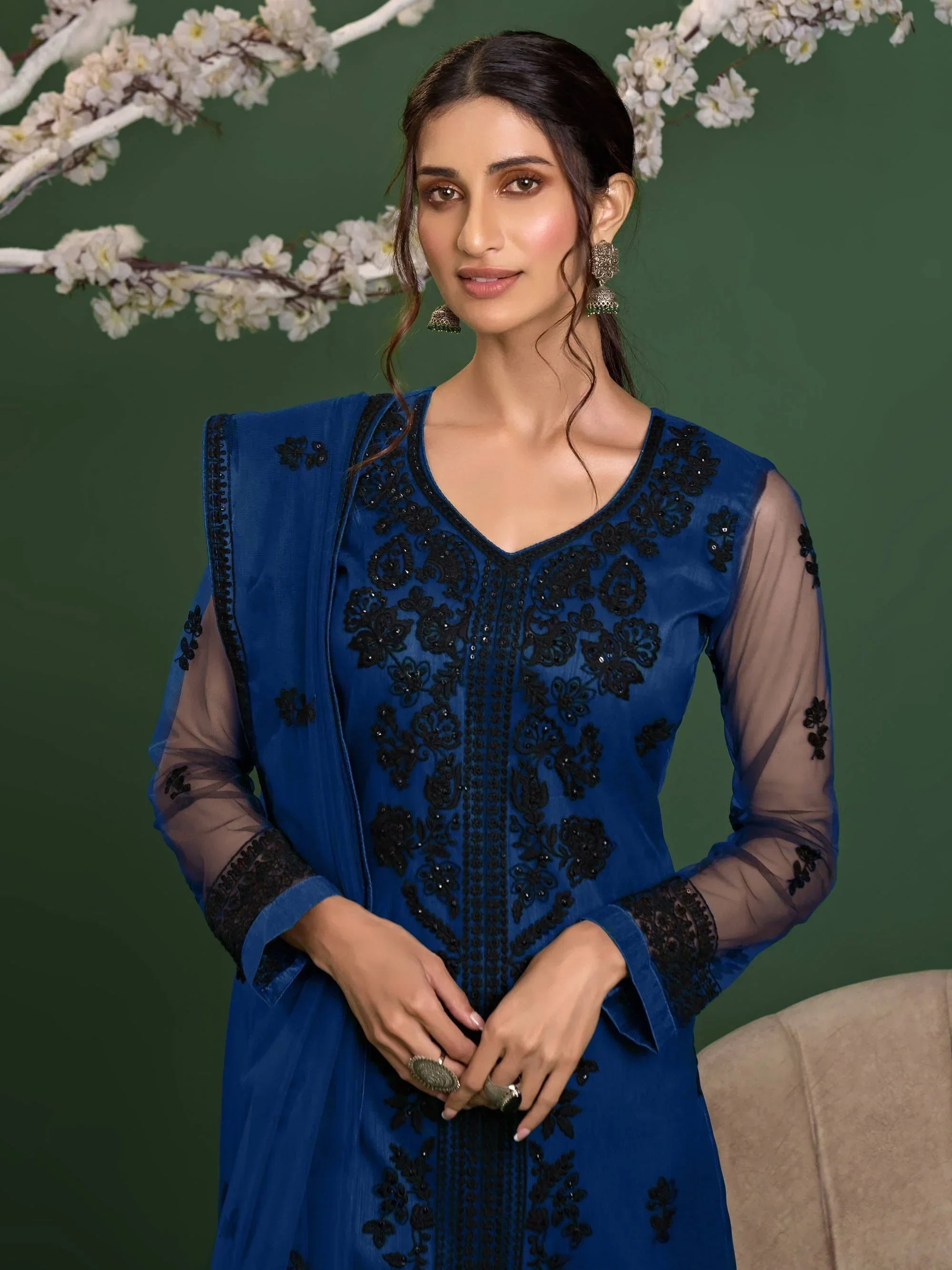 Woman wearing blue embroidered salwar kameez with sheer sleeves and statement earrings