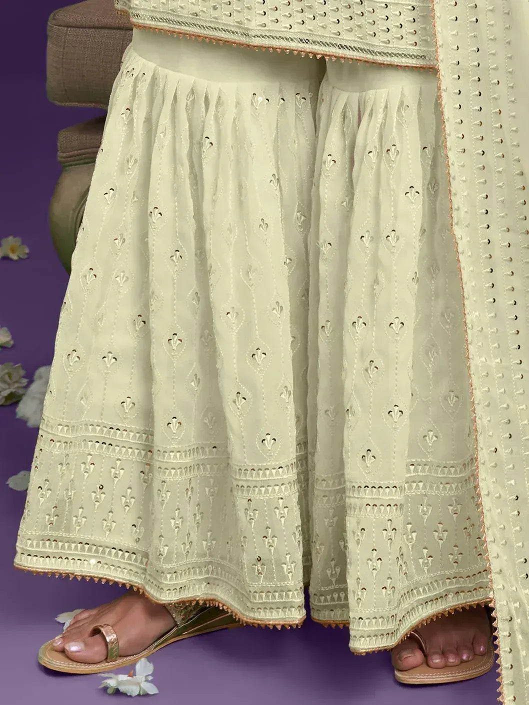 Elegant cream ethnic palazzo with intricate embroidery and golden trim, paired with flat sandals.