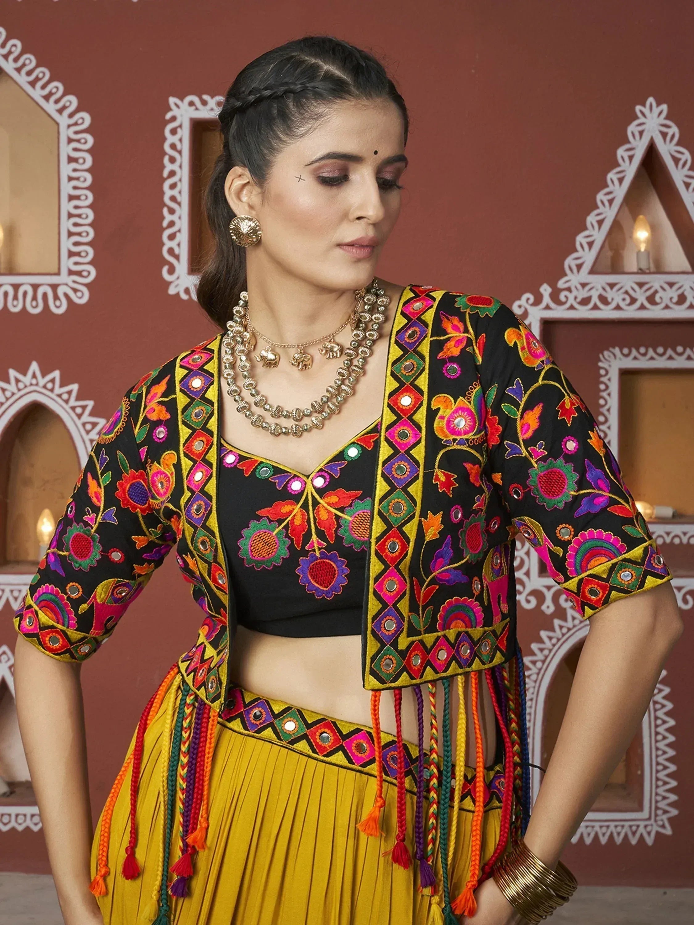 Black and yellow embroidered ethnic crop top with mirror work and colorful tassels, paired with pleated skirt