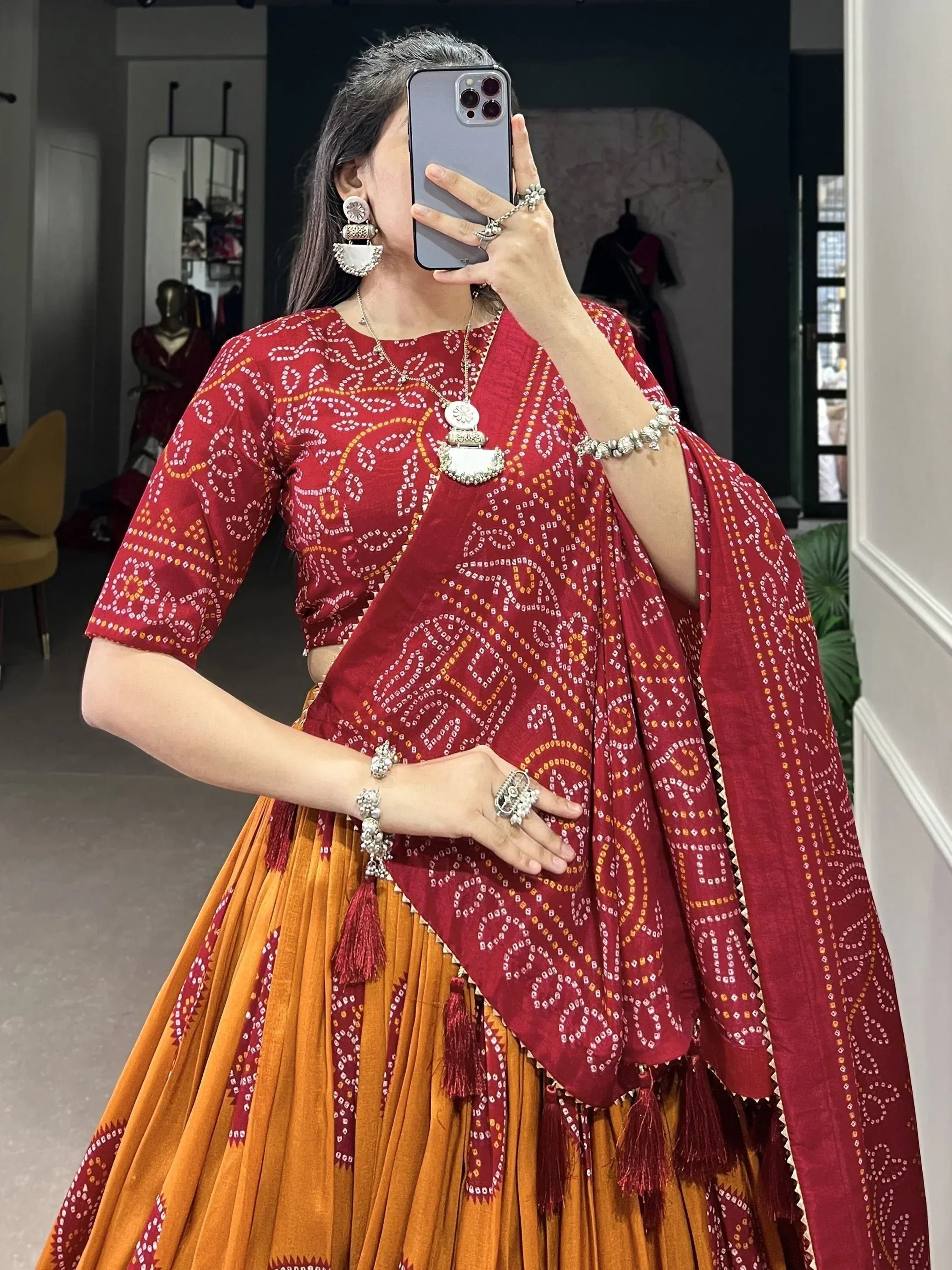 Red and orange printed lehenga choli with tassels, styled with silver jewelry for ethnic wear