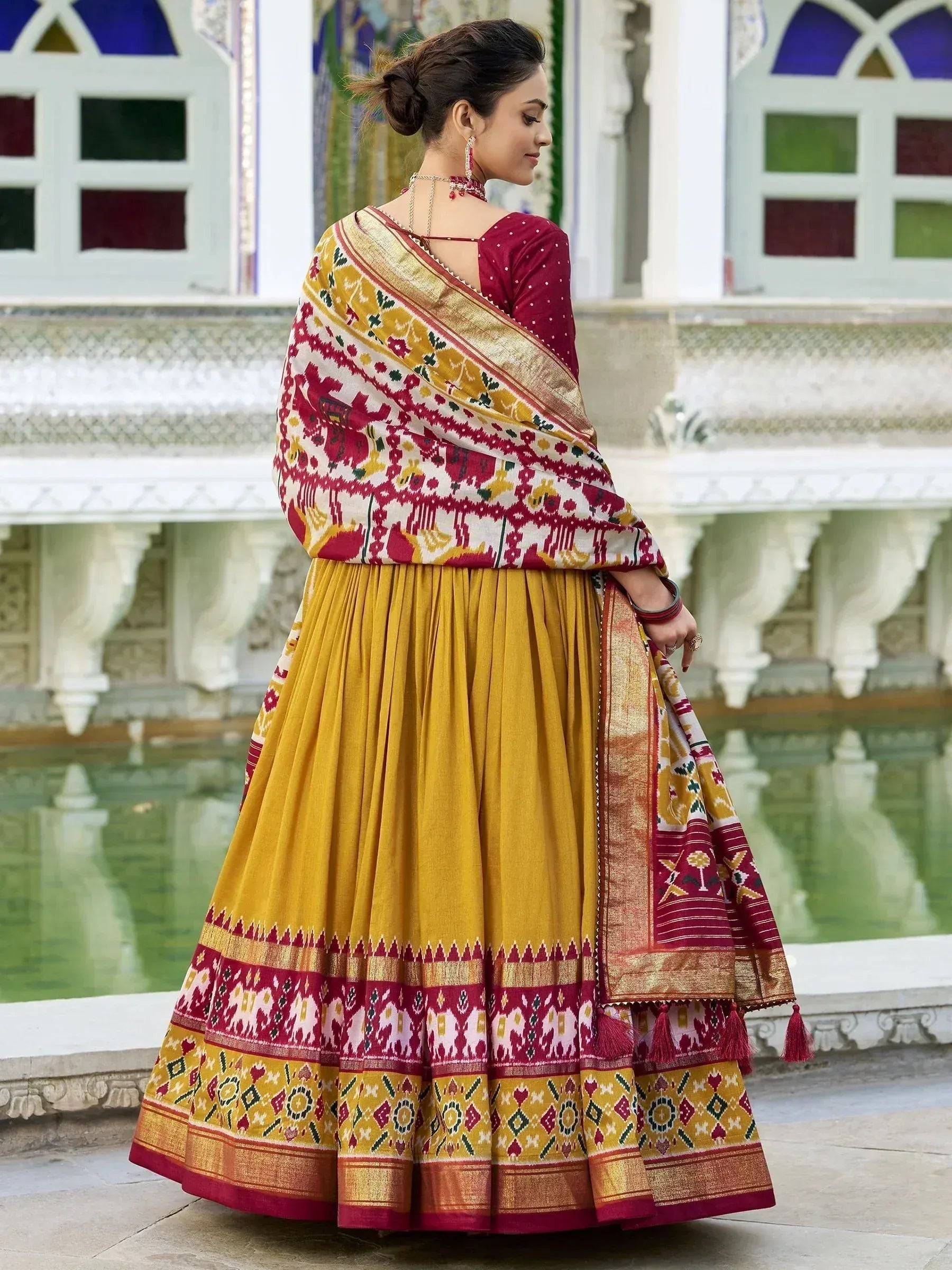 Woman in maroon and mustard yellow ethnic lehenga choli with intricate ikat print, perfect for Indian weddings and festivals