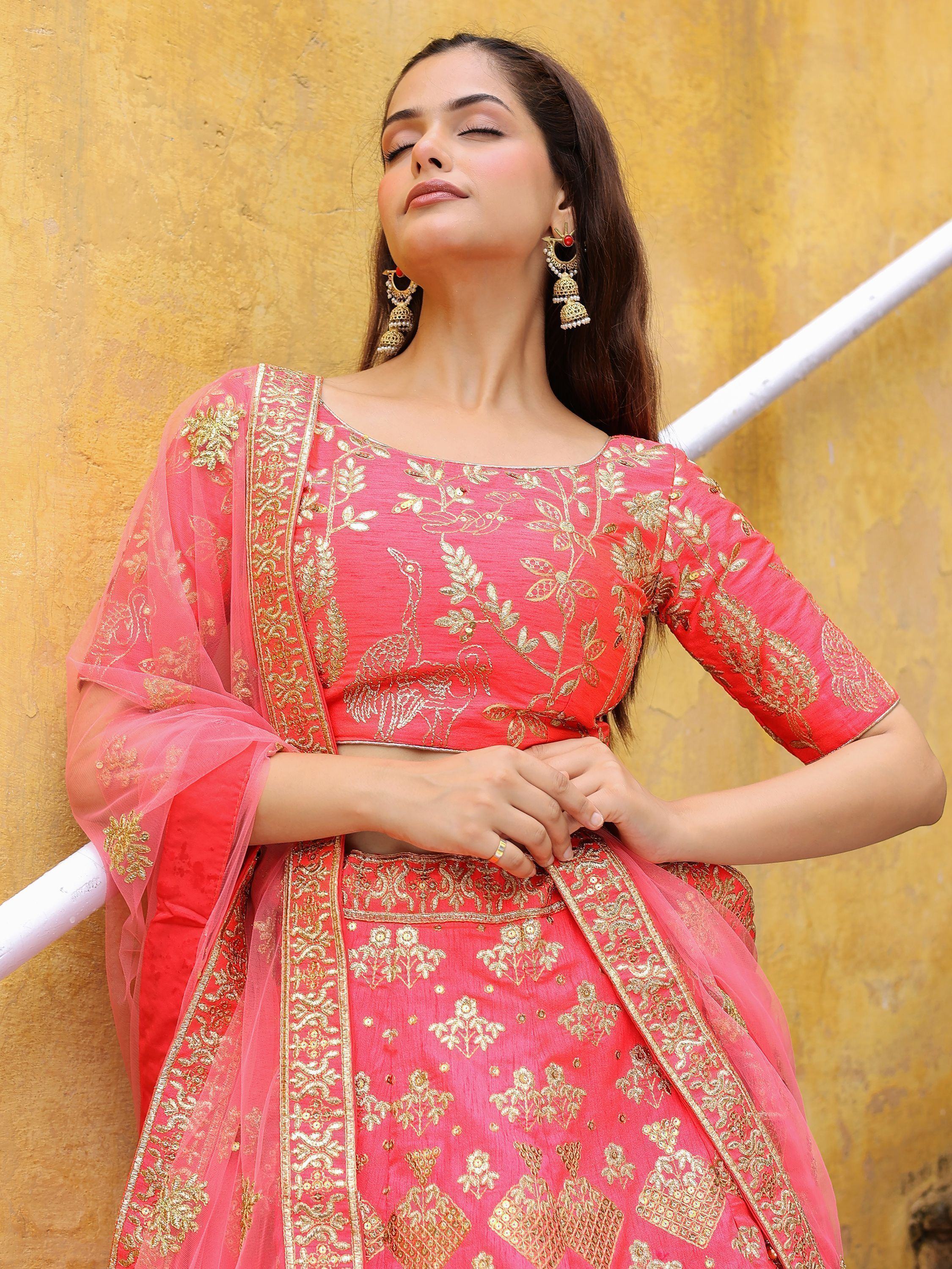 Pink embroidered lehenga choli with gold floral and peacock motifs, paired with matching dupatta and jhumka earrings.