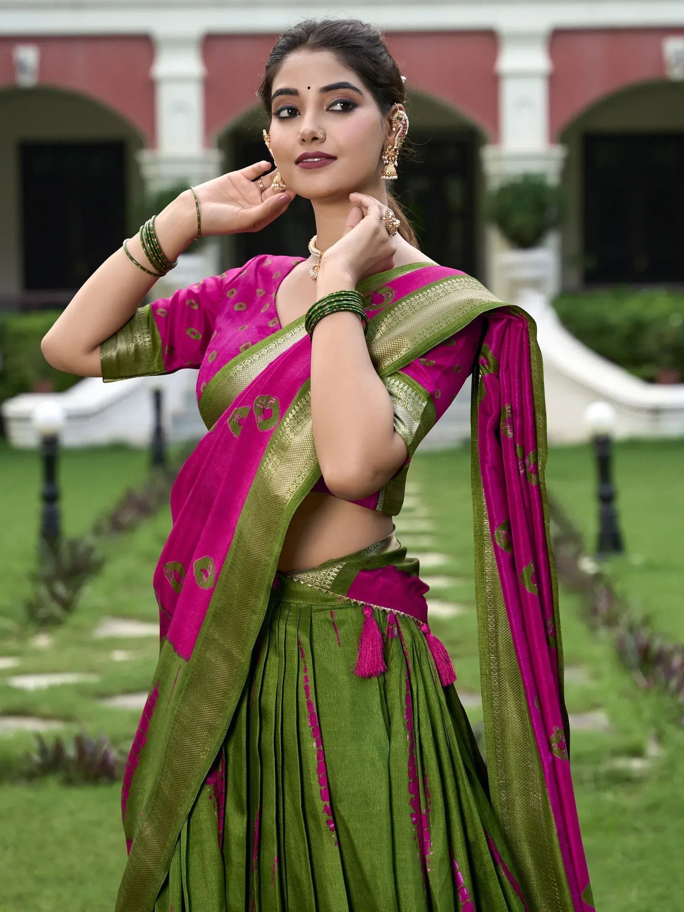 Woman in vibrant pink and green designer lehenga choli with gold embroidery, perfect for Indian ethnic wear occasions