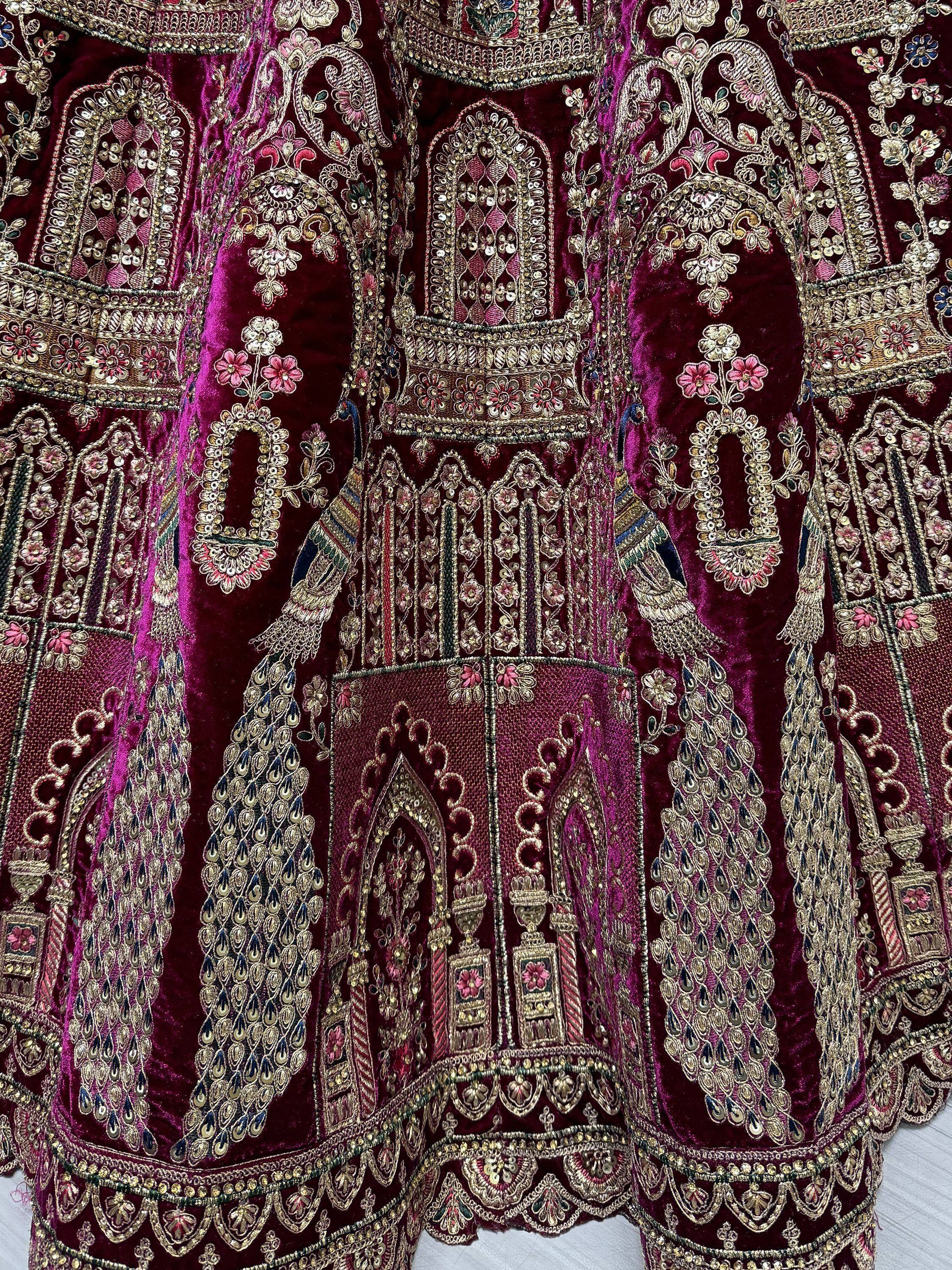 Luxury maroon velvet lehenga with intricate gold embroidery, peacock motifs, and floral designs for Indian ethnic wear.