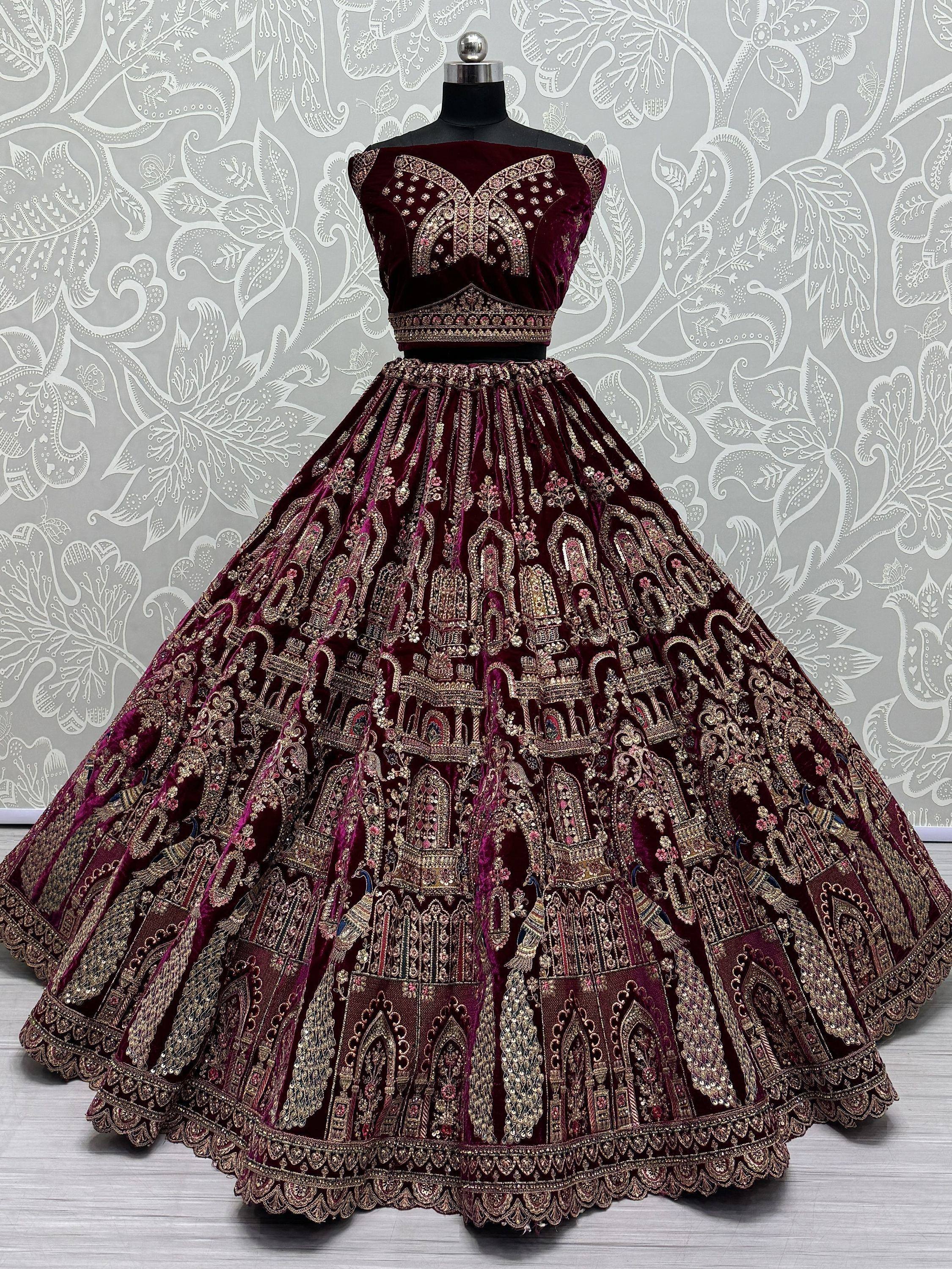 Burgundy velvet lehenga choli with heavy gold embroidery, perfect for Indian weddings and festive occasions.