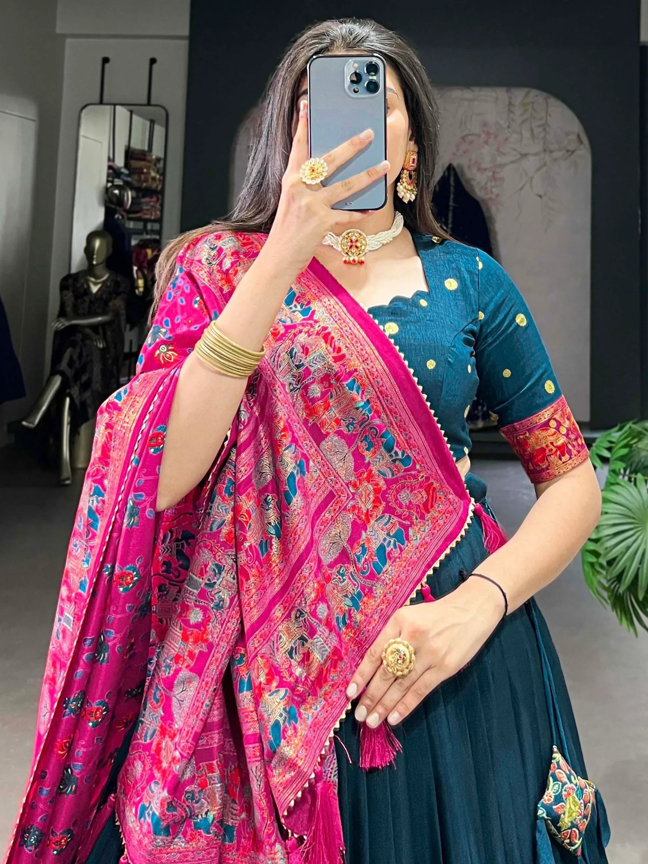 Woman in teal designer lehenga choli with vibrant pink embroidered dupatta, traditional Indian ethnic wear