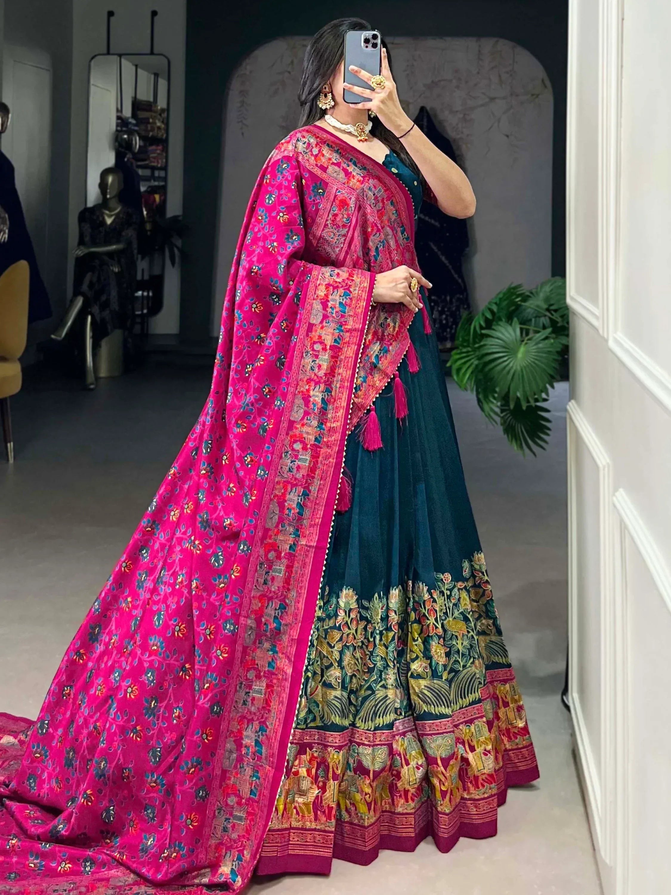 Woman in vibrant pink and teal embroidered lehenga choli with floral dupatta, perfect for Indian ethnic wear occasions