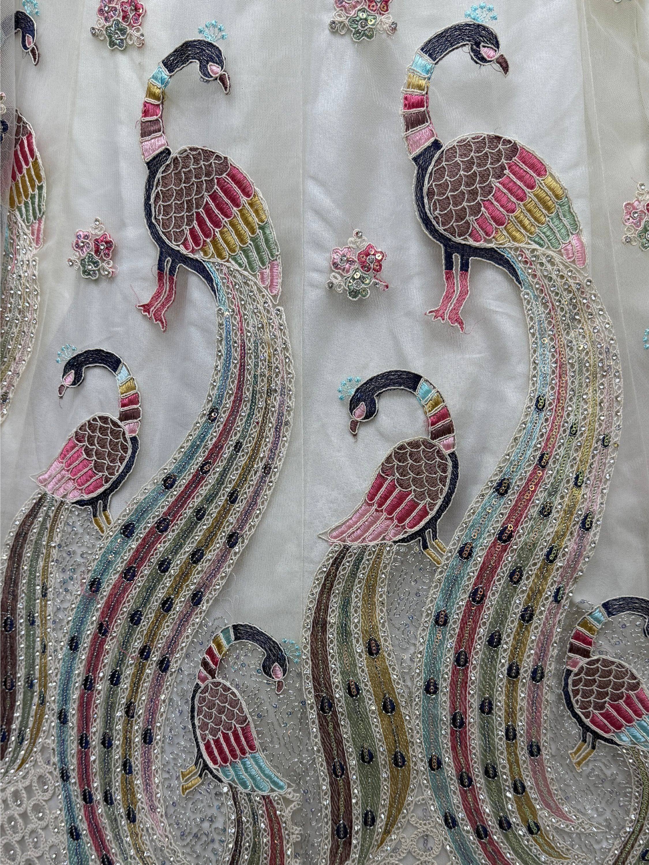 Colorful peacock embroidery with sequins on white ethnic wear fabric, perfect for designer lehenga or saree.