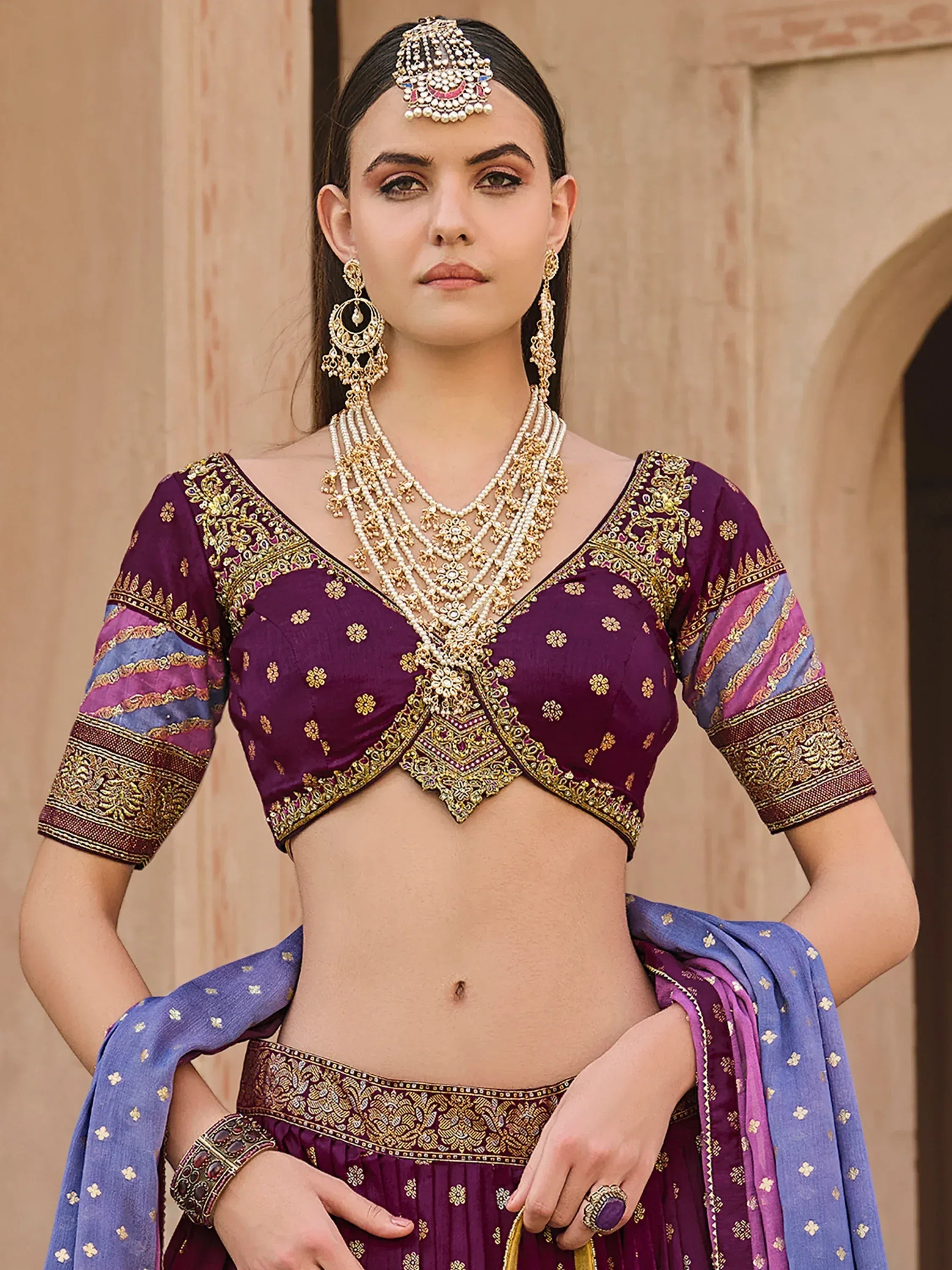 Purple and blue designer lehenga choli with gold embroidery and traditional Indian jewelry