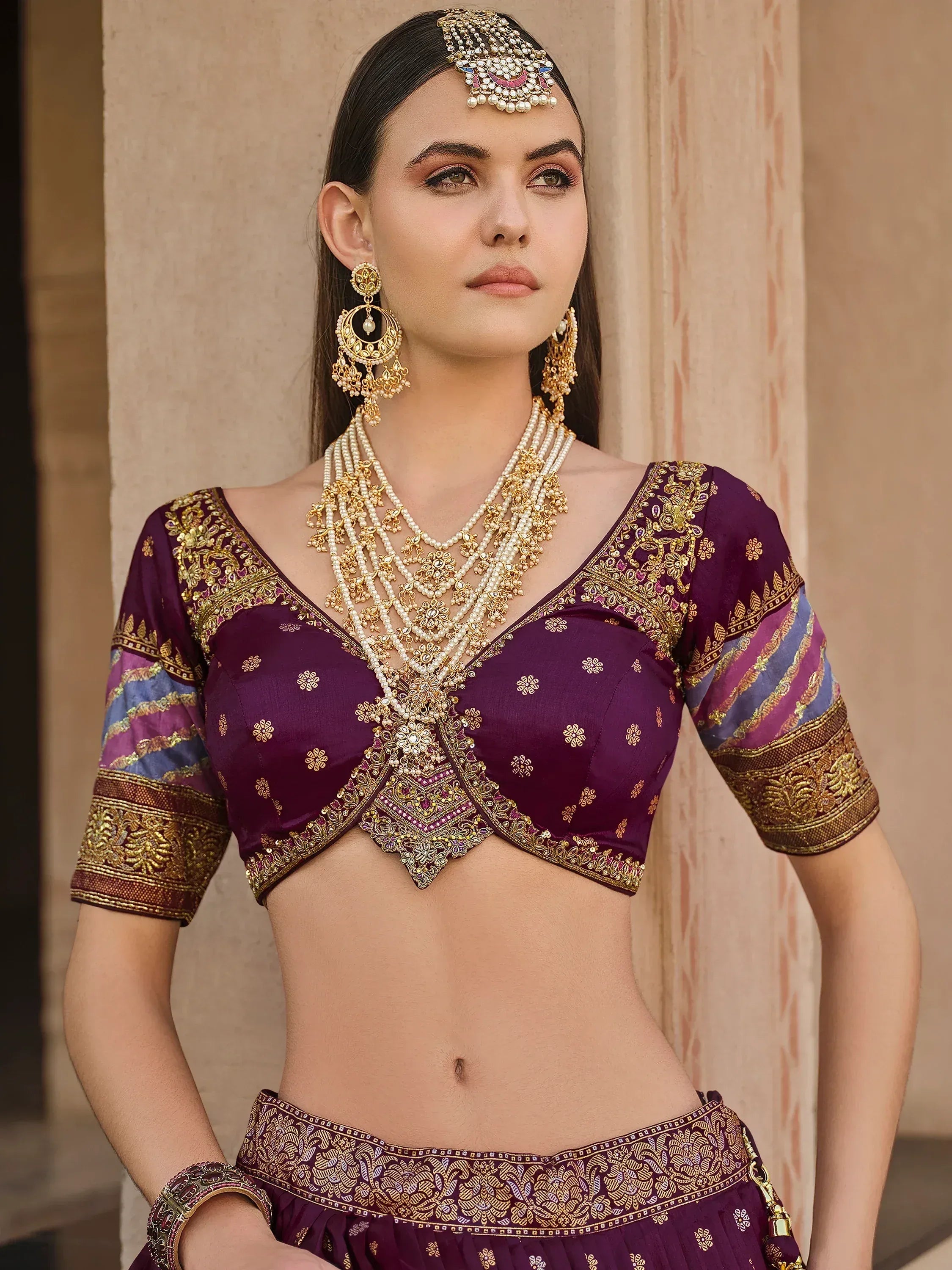 Elegant purple lehenga choli with gold embroidery and traditional Indian jewelry for festive occasions