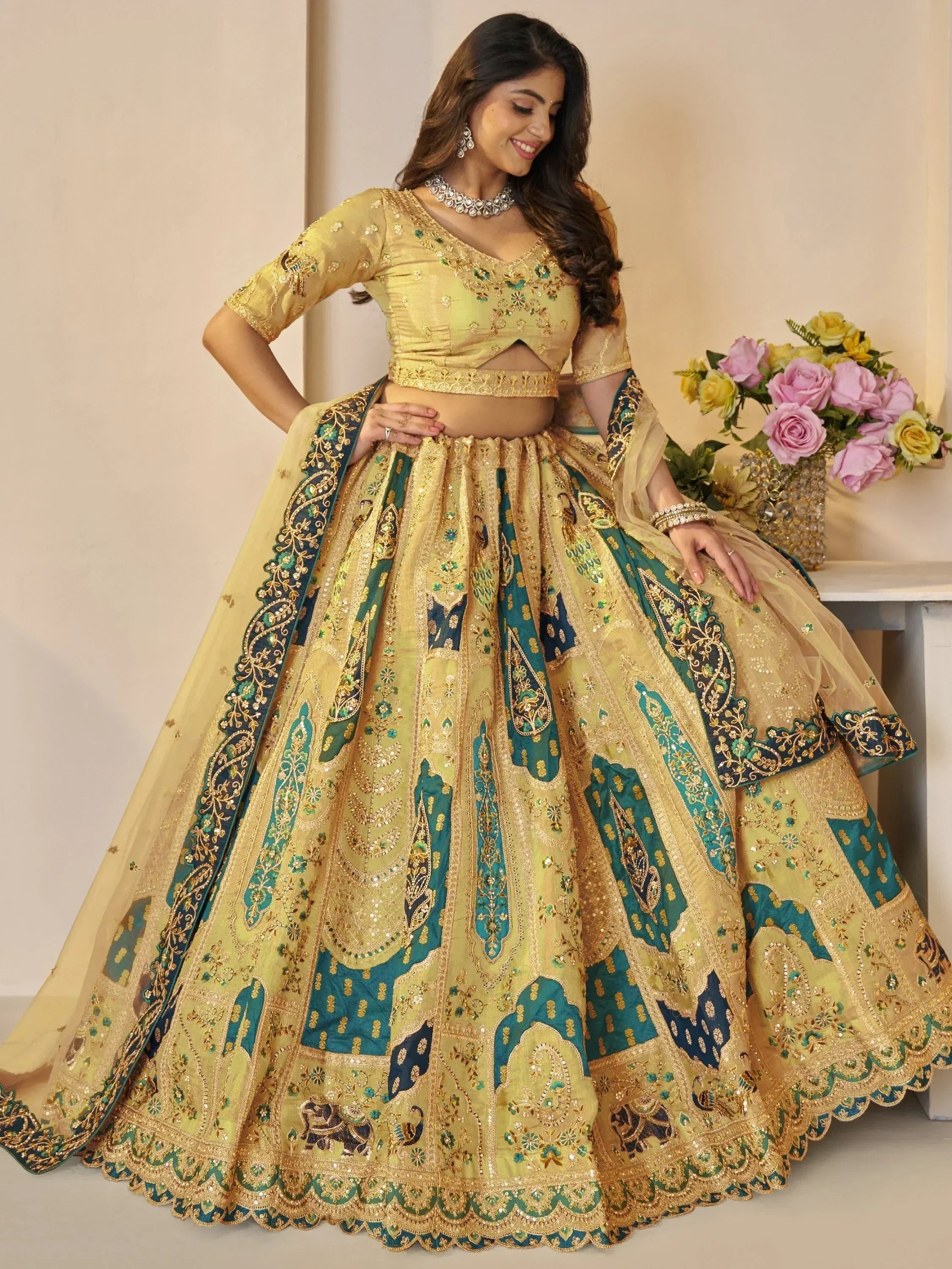 Elegant gold and teal embroidered lehenga choli with intricate floral and paisley designs, perfect for Indian weddings and festive occasions.