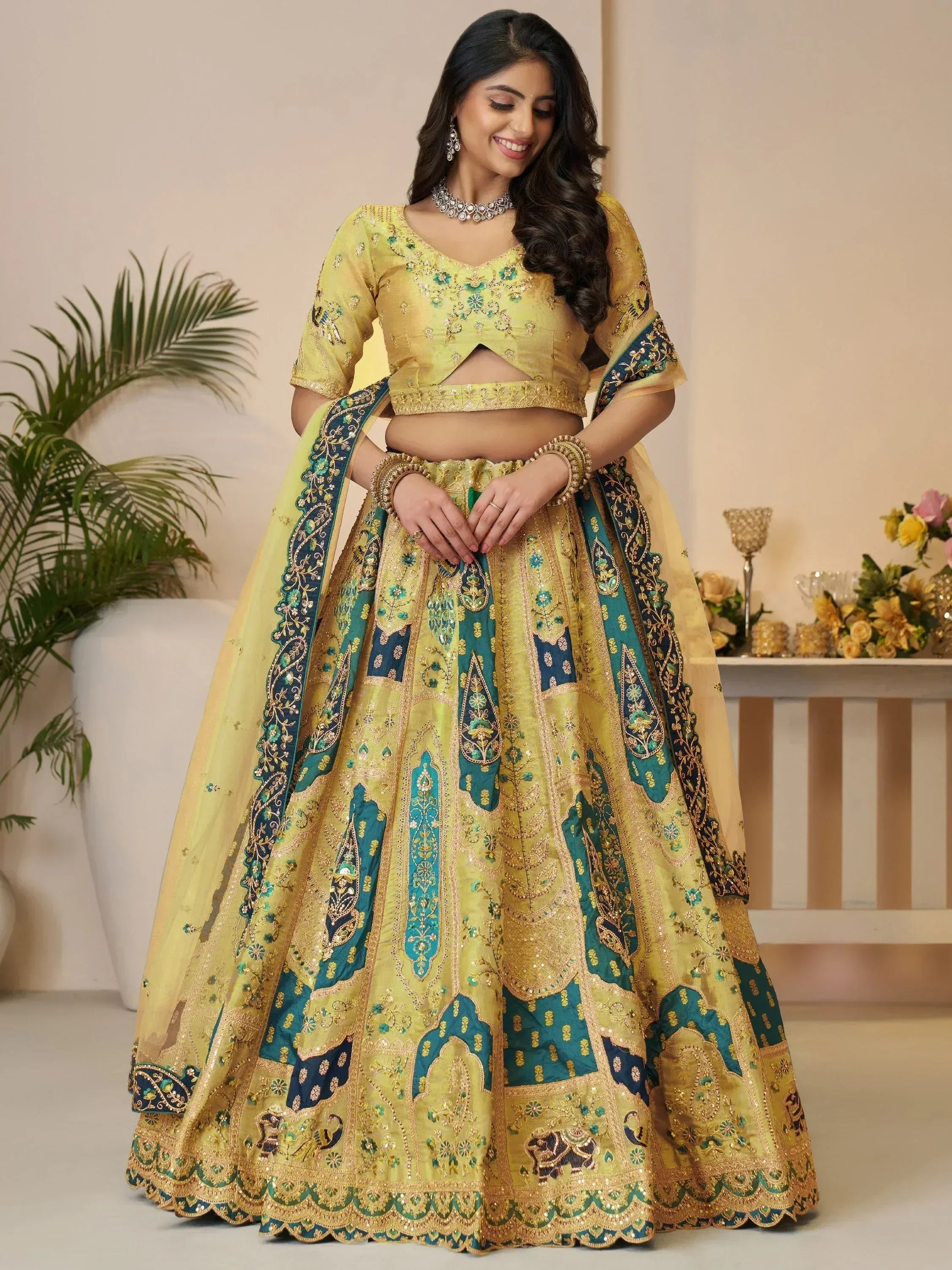 Yellow and teal embroidered lehenga choli with gold detailing, perfect for Indian weddings and festive occasions.
