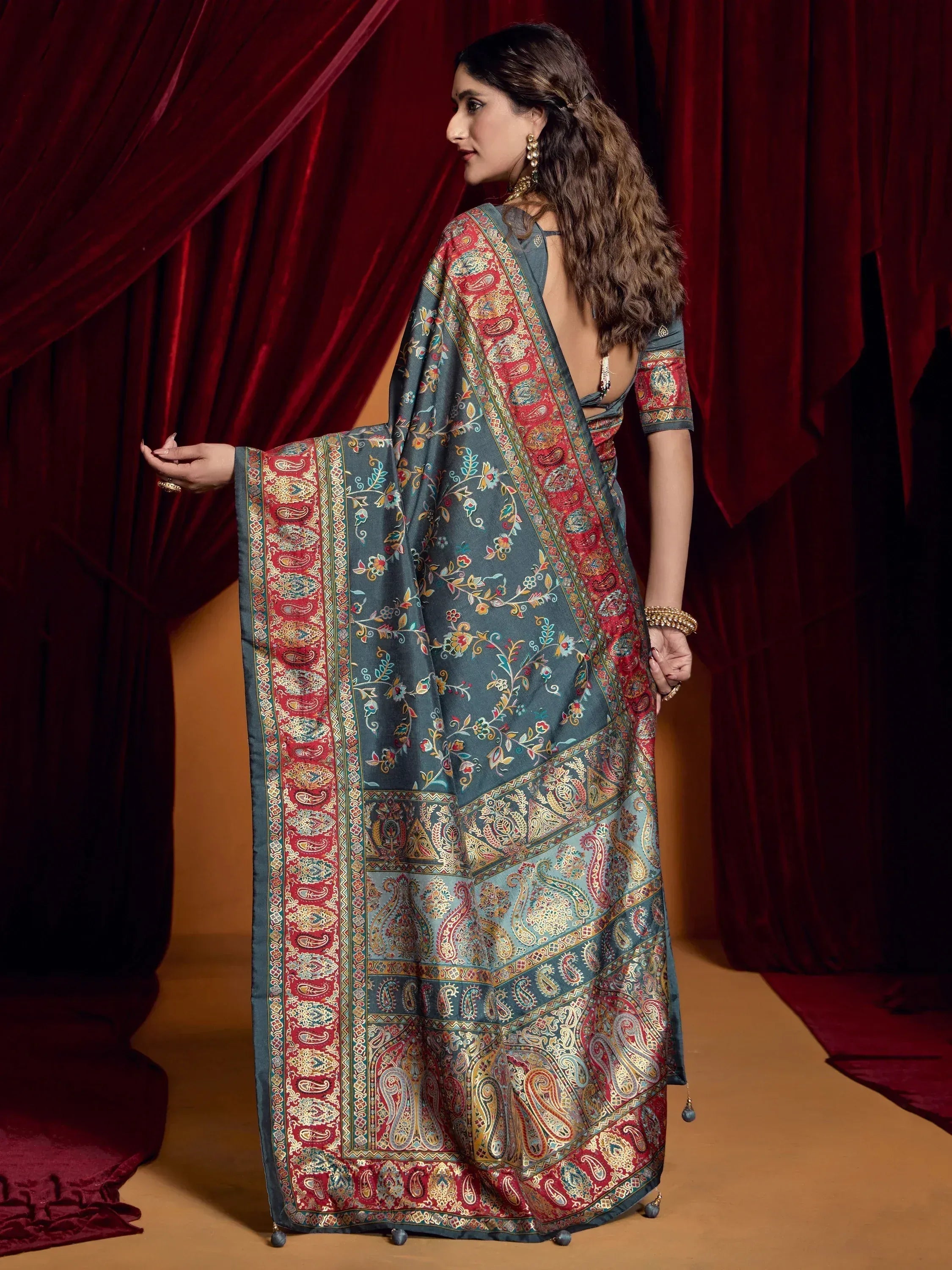 Woman in elegant grey saree with red paisley border, floral print, and backless blouse, perfect for Indian ethnic occasions.